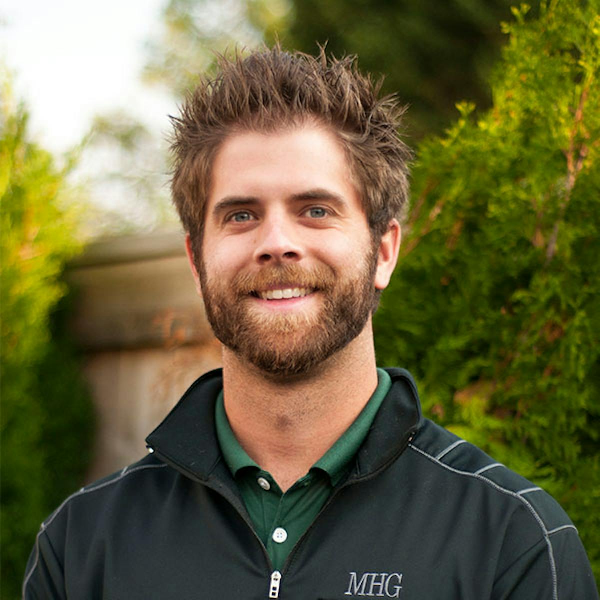 a man wearing a green shirt smiling for a photo