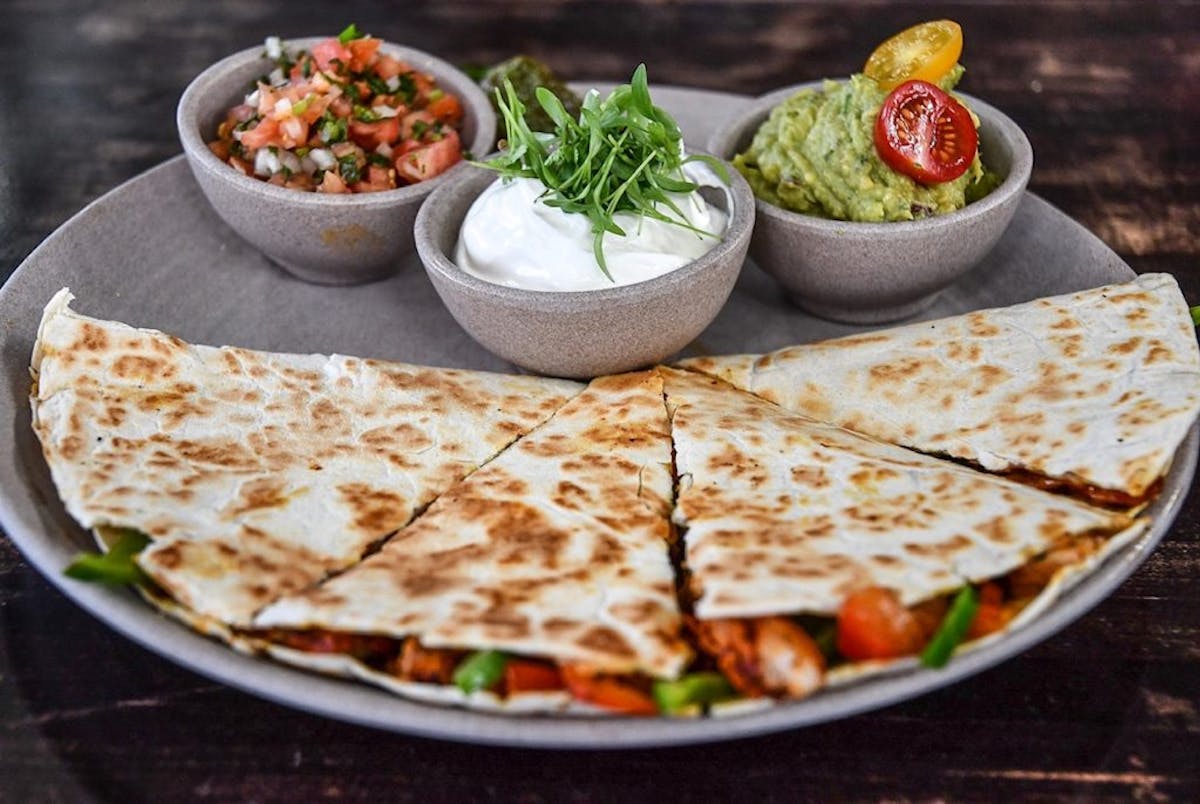 a quesadilla and dips on a plate