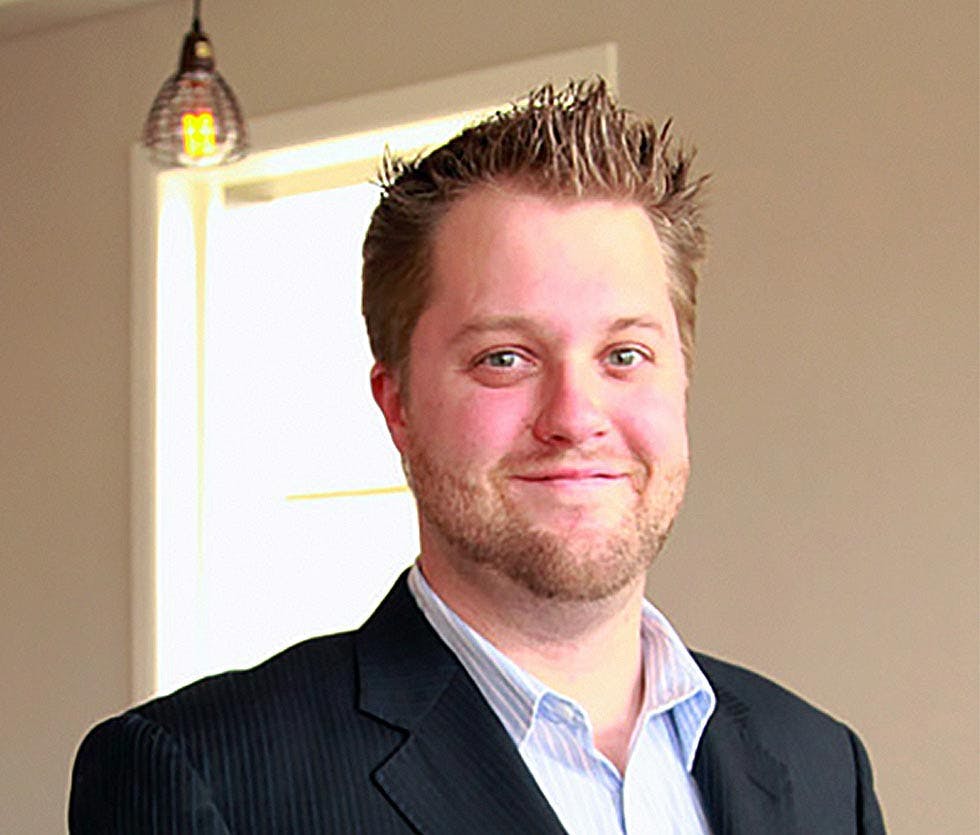 a man wearing a suit and tie smiling at the camera