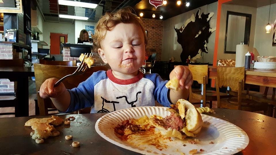 a little boy sitting at a table eating food