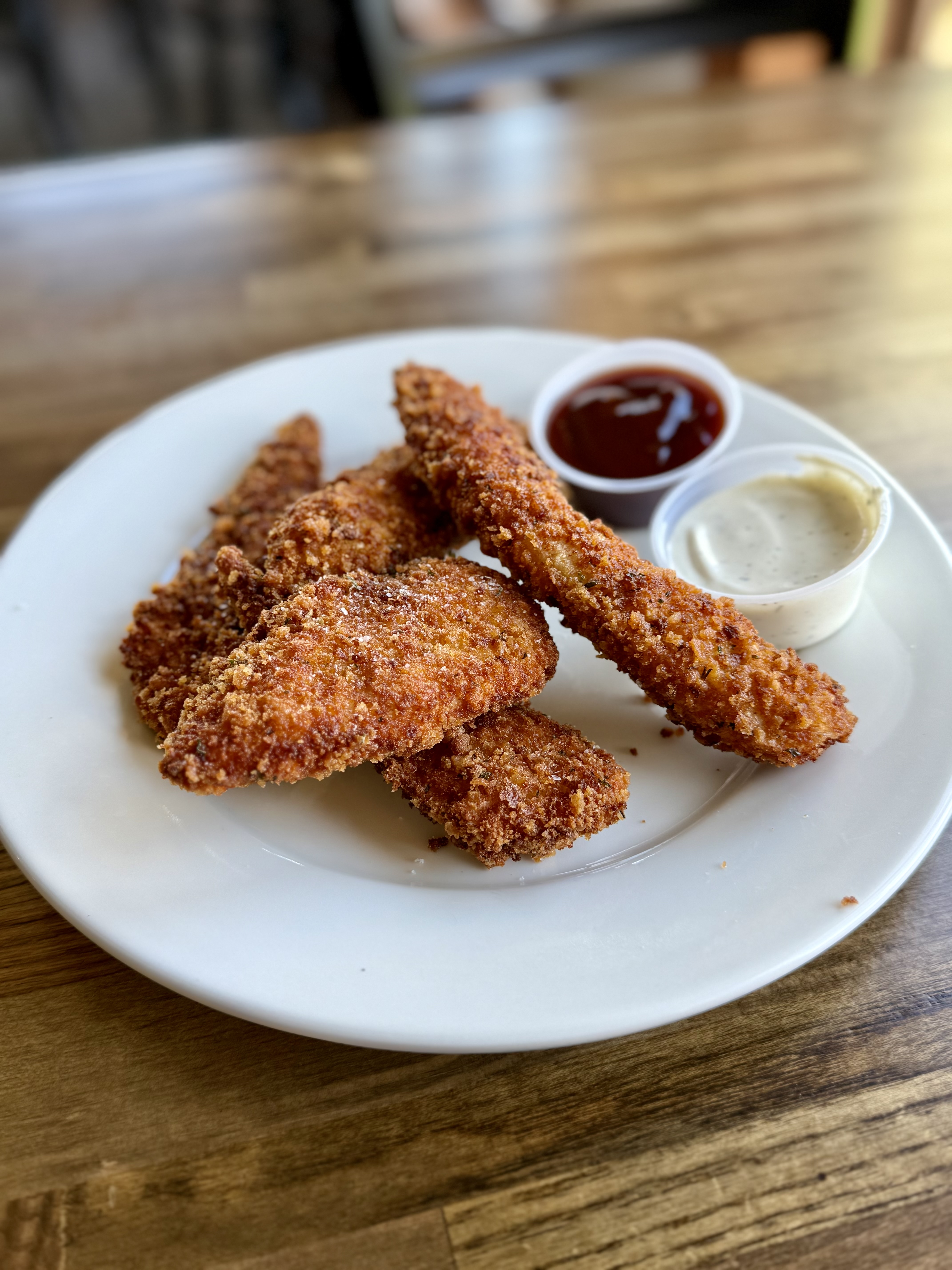 a plate of fried chicken strips with sauces
