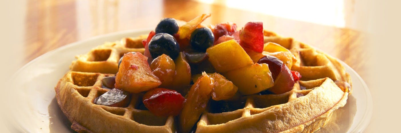 a close up of a waffle topped with fruits