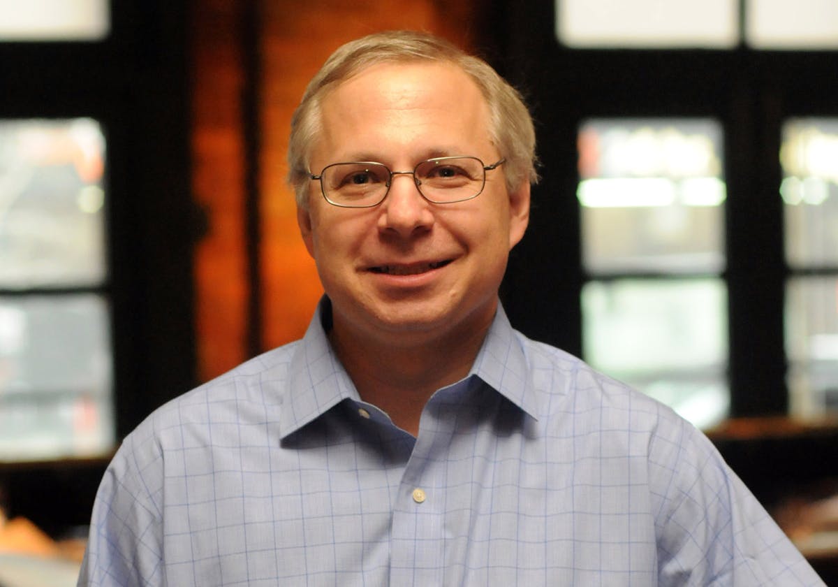 a man wearing glasses and smiling at the camera