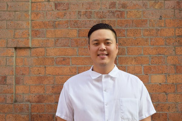 a man standing in front of a brick wall