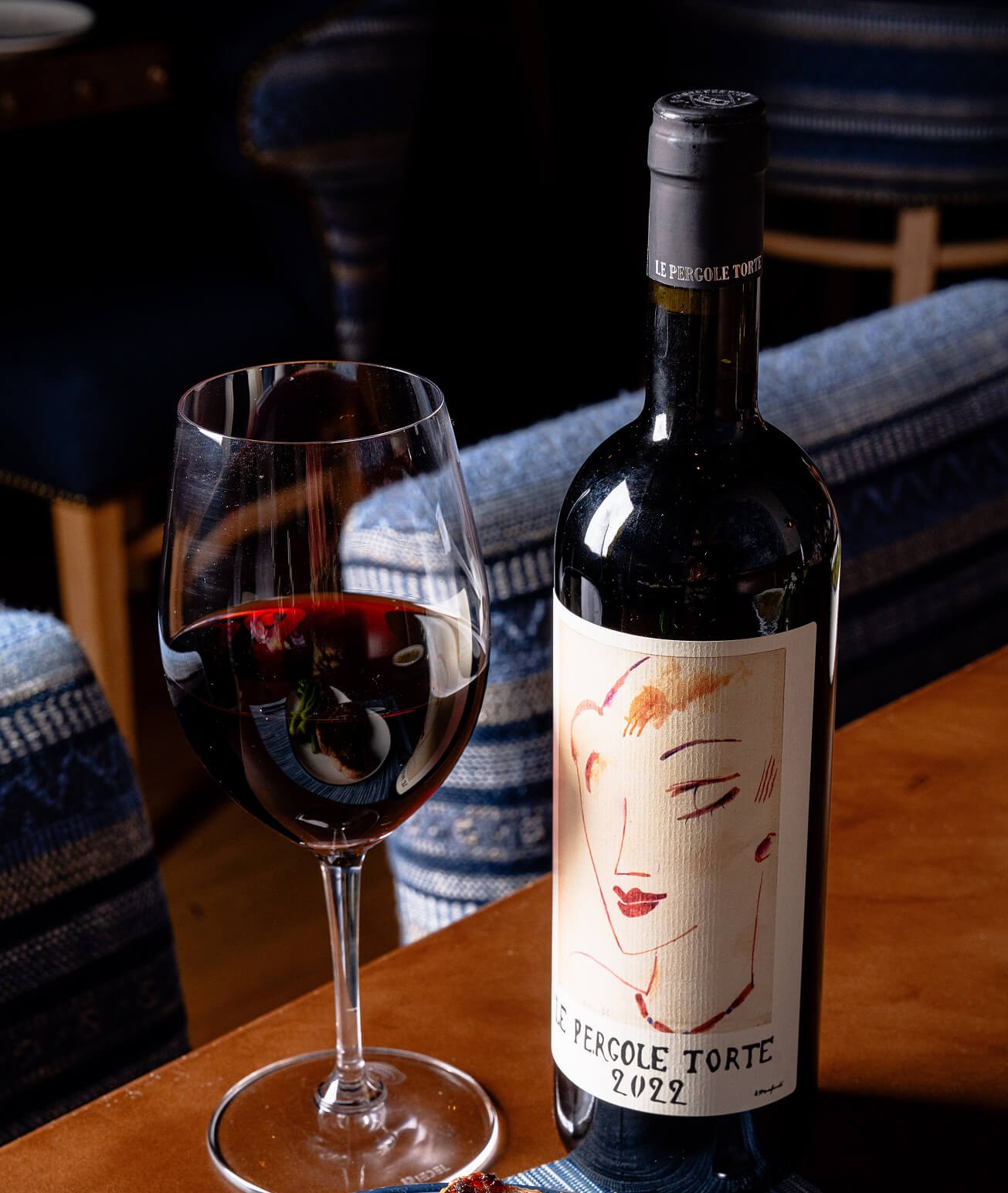 Bottle and glass of Montevertine Le Pergole Torte red wine on a table.