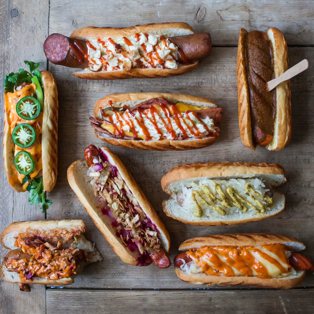a bunch of hot dogs with different toppings