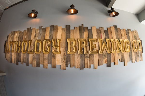 wooden slated sign on grey wall under light sconces