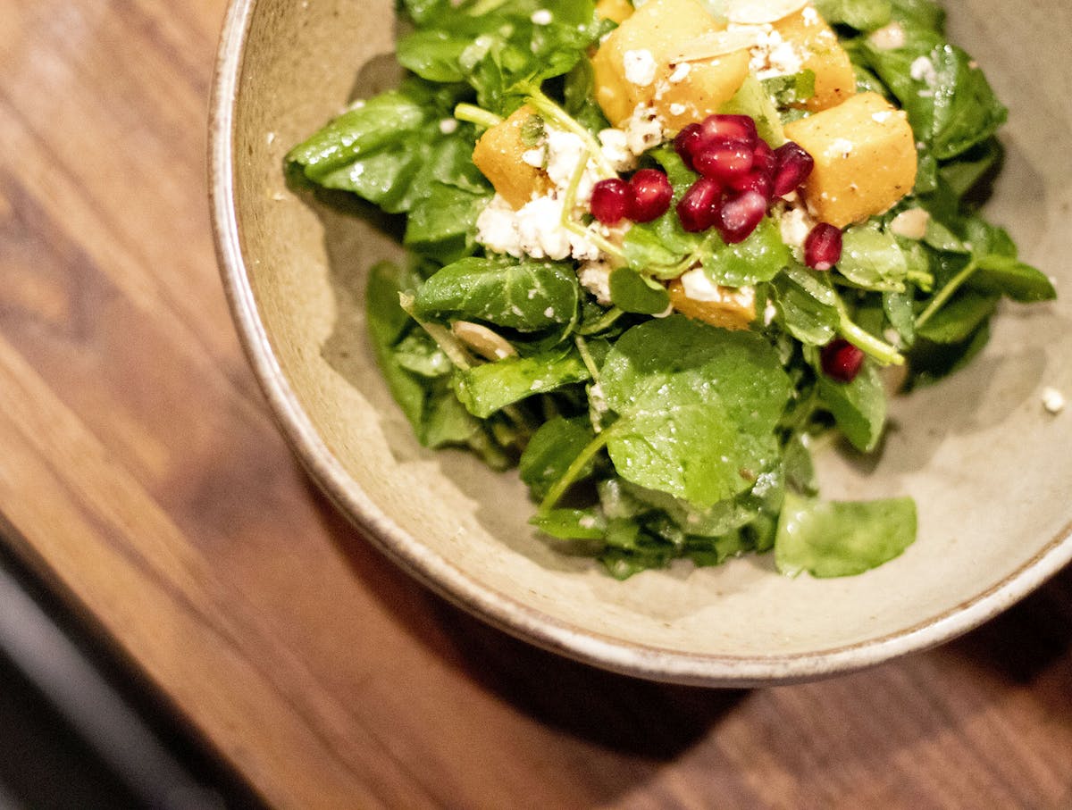 a plate of salad with a green salad on top of a wooden table