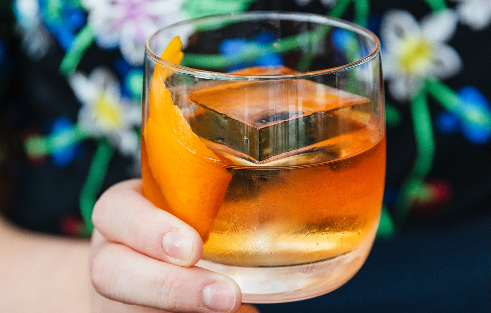 a hand holding a glass of orange juice