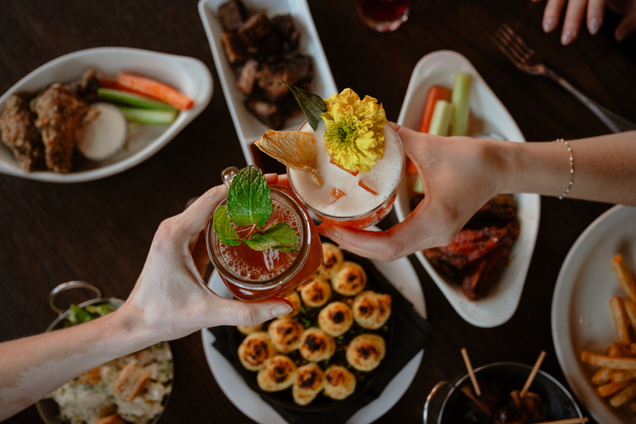a group of hands holding drinks with a flower on them