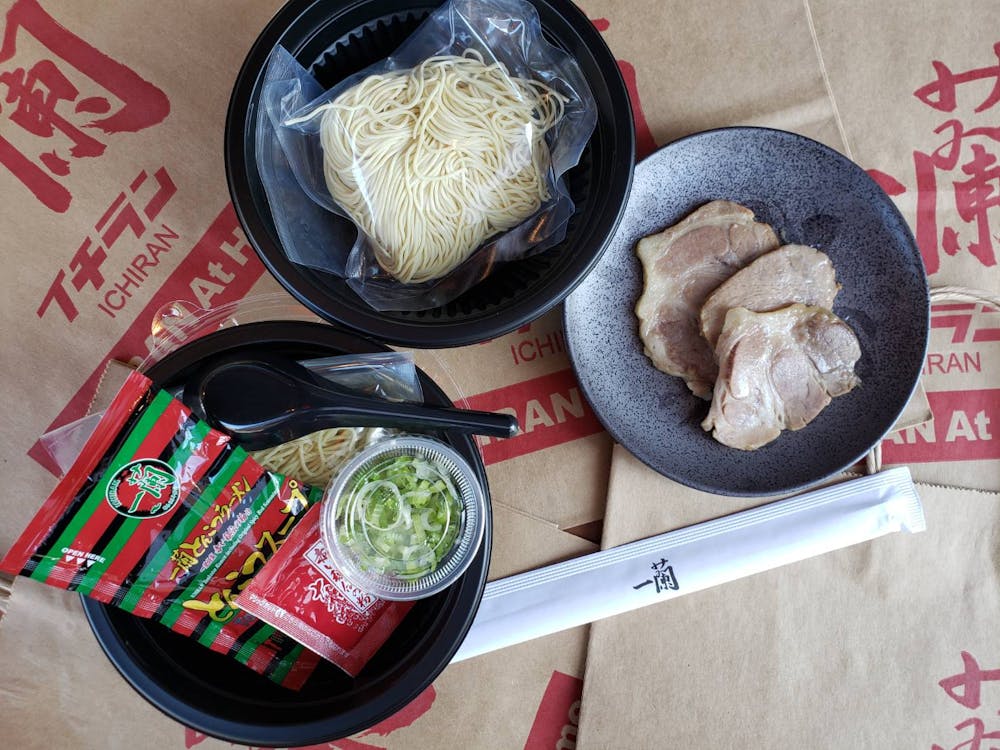 Top view of Fresh Ramen on plates - includes fresh, uncooked noodles, chashu pork slices, scallions, soup concentrate, Original Spicy Red Seasoning, disposable chopsticks, plastic ramen spoon
