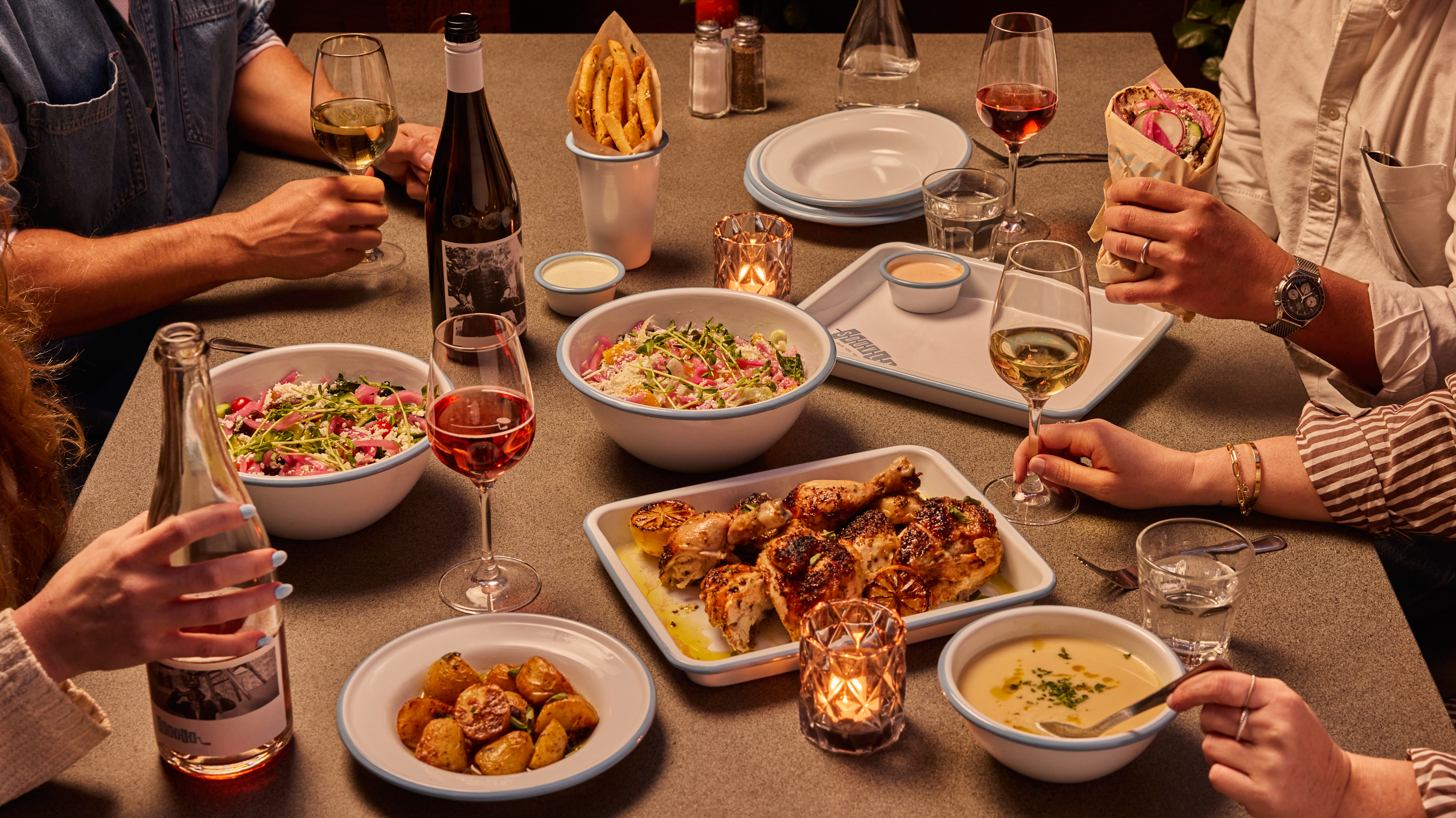 a group of people eating at a table with food and drinks