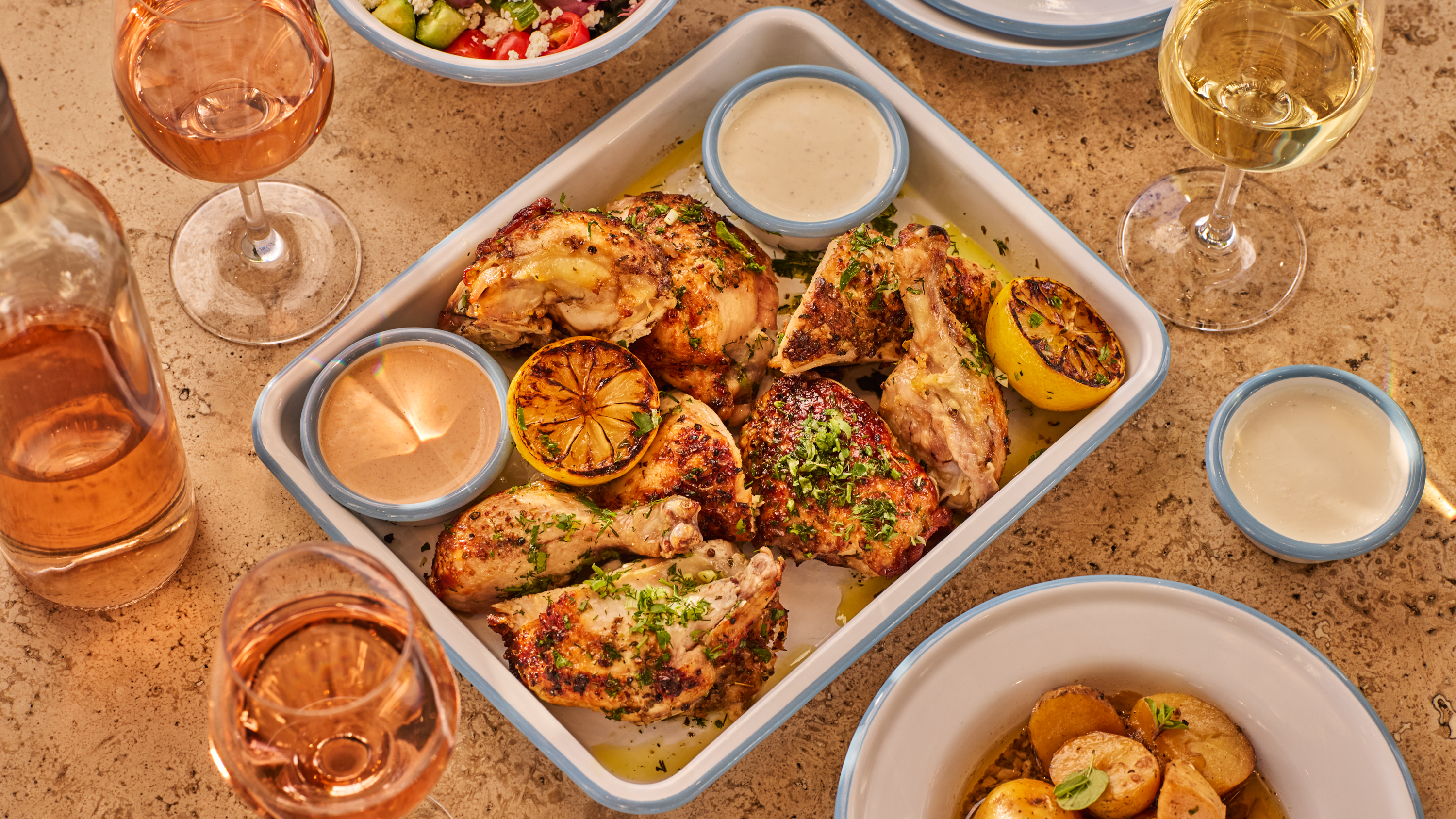 a tray of food with a side of salad and glasses of wine