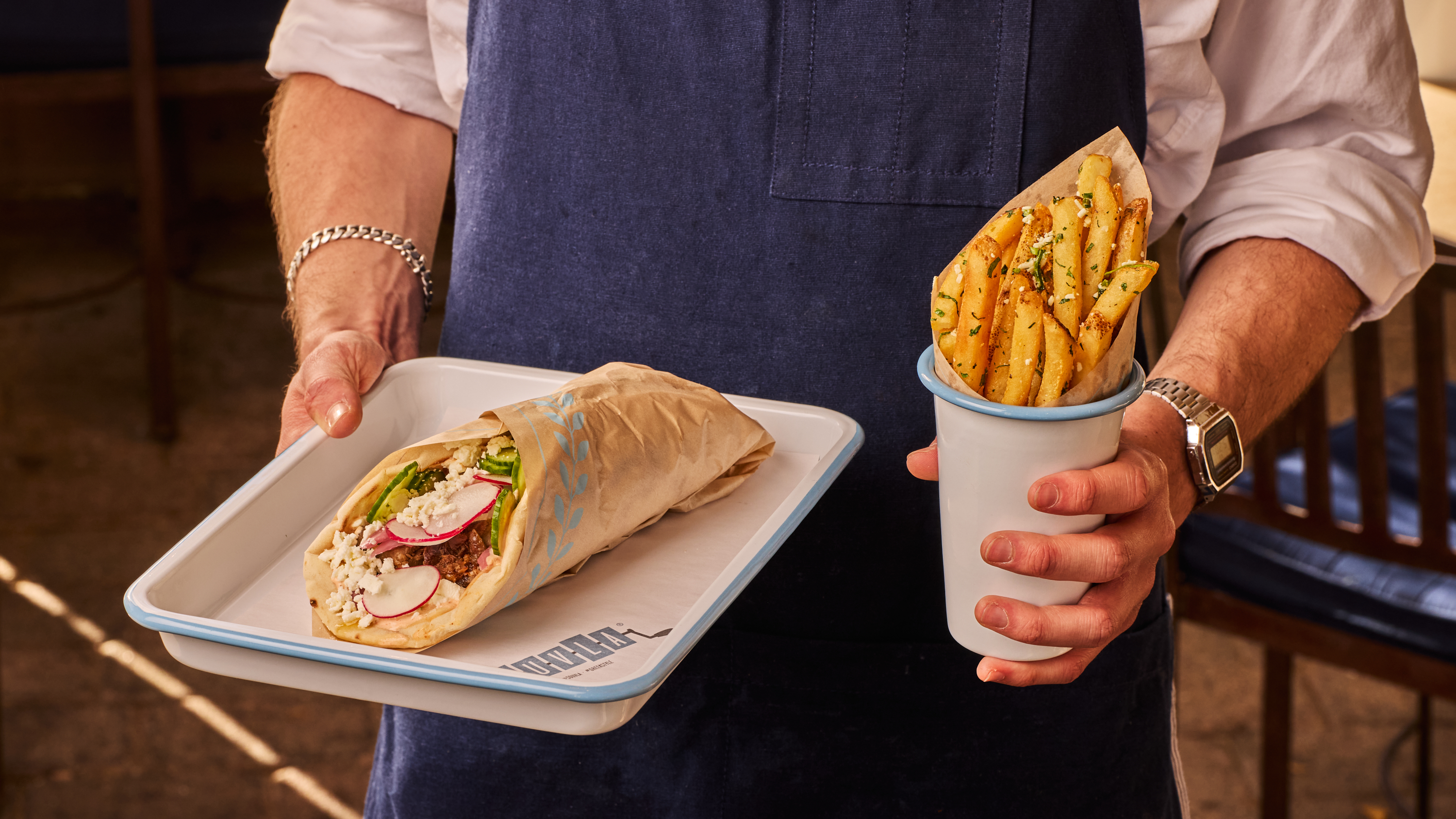 a person holding a tray of food and a cup of fries