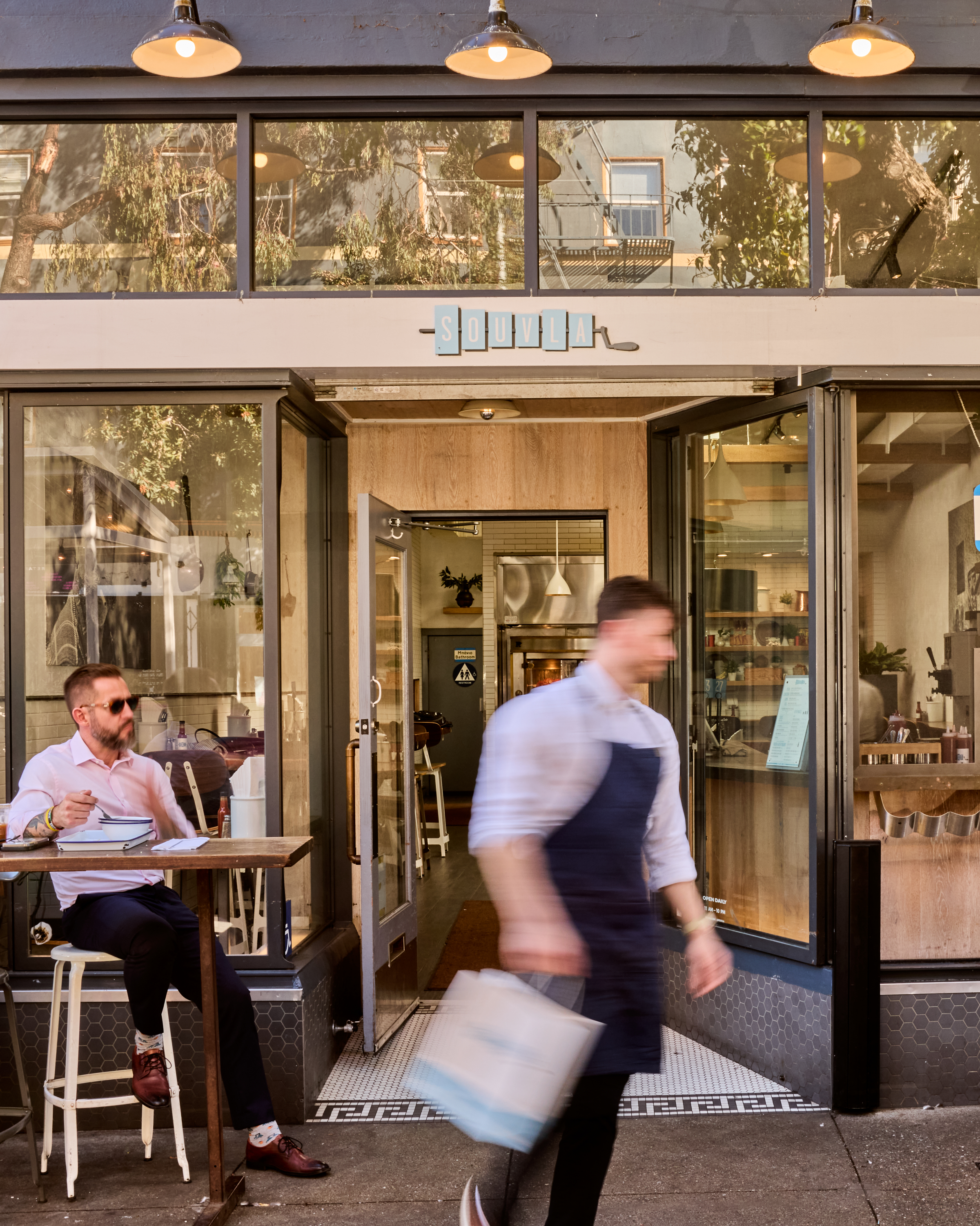a man in an apron walking out of a restaurant