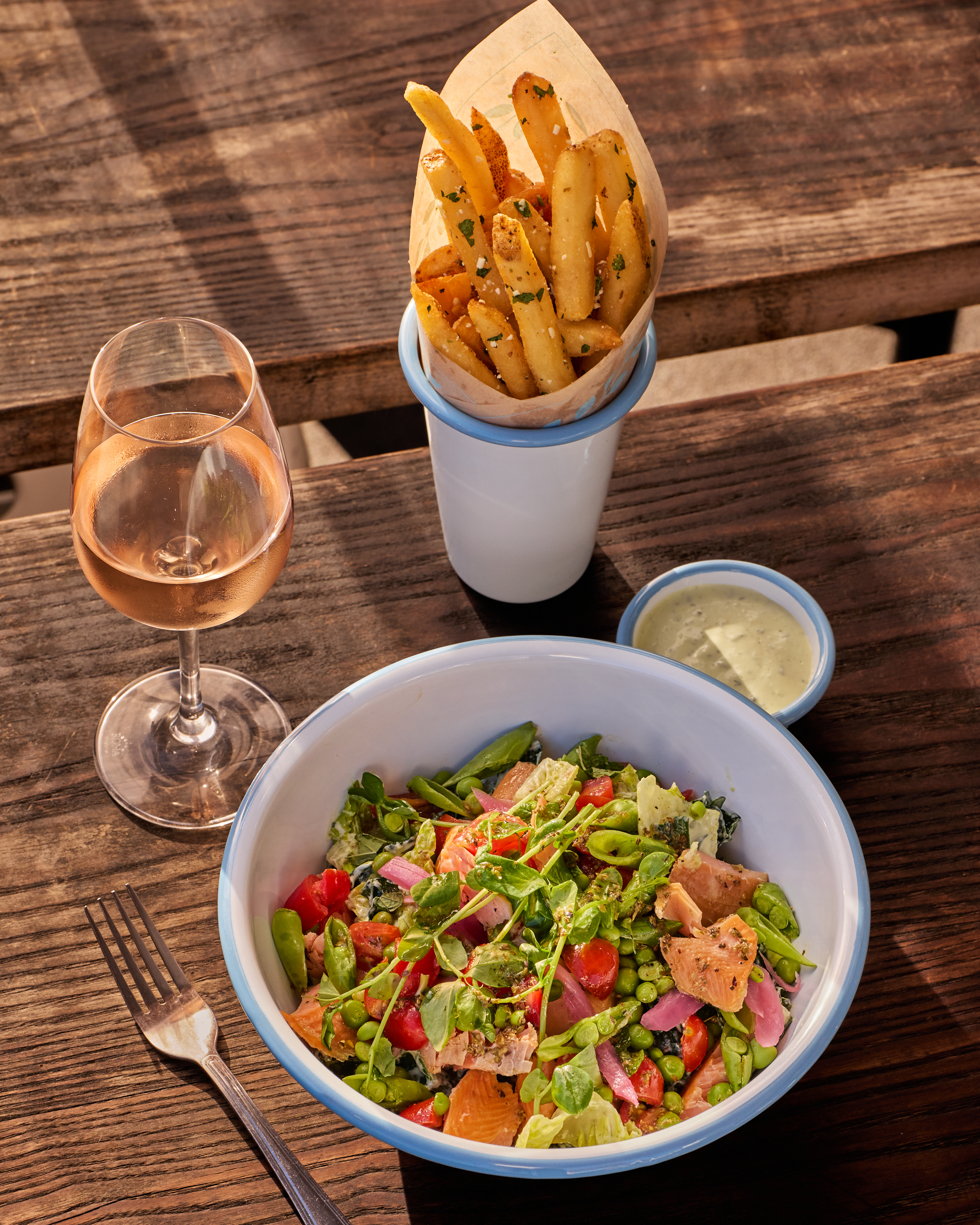 a bowl of salad and french fries on a table