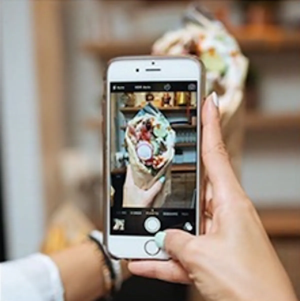 a hand holding a phone taking a picture of food