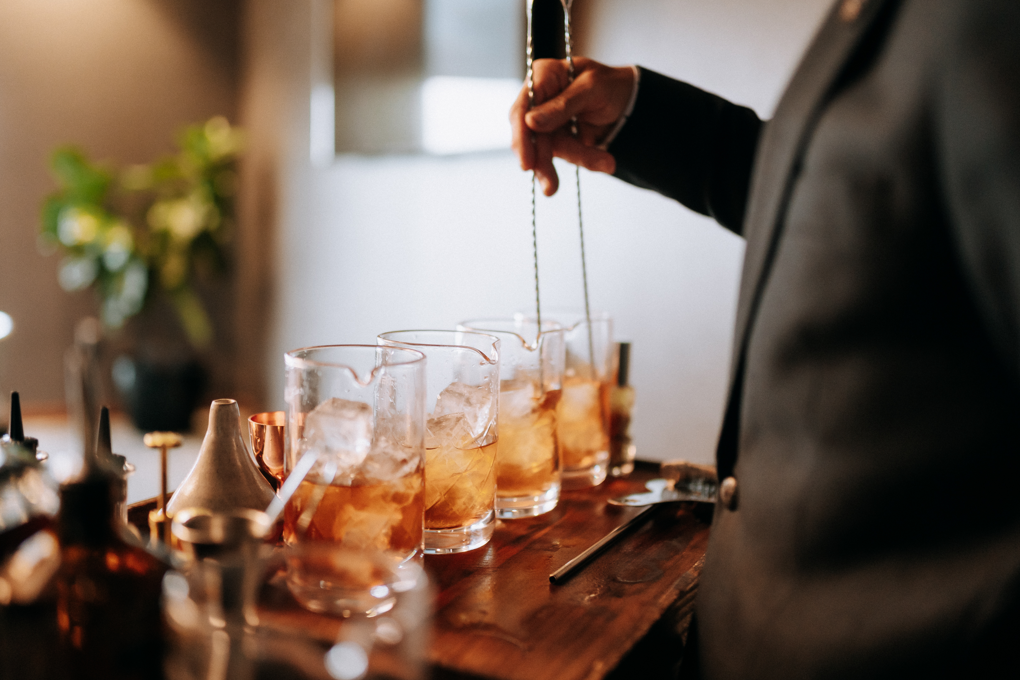 a person holding a long metal tong over a row of glasses with ice