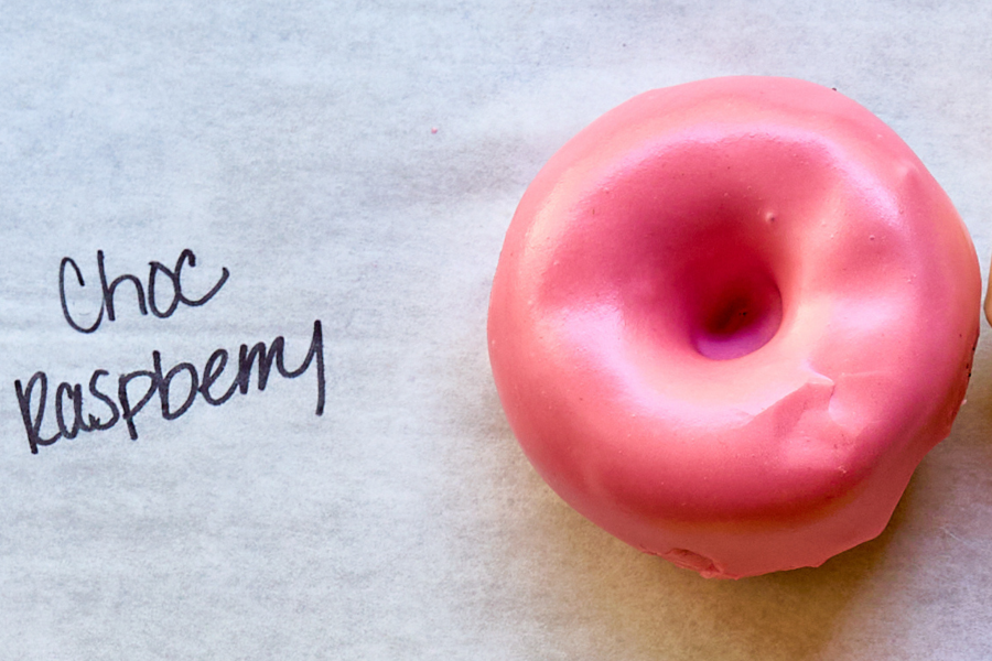 a pink donut on a white surface