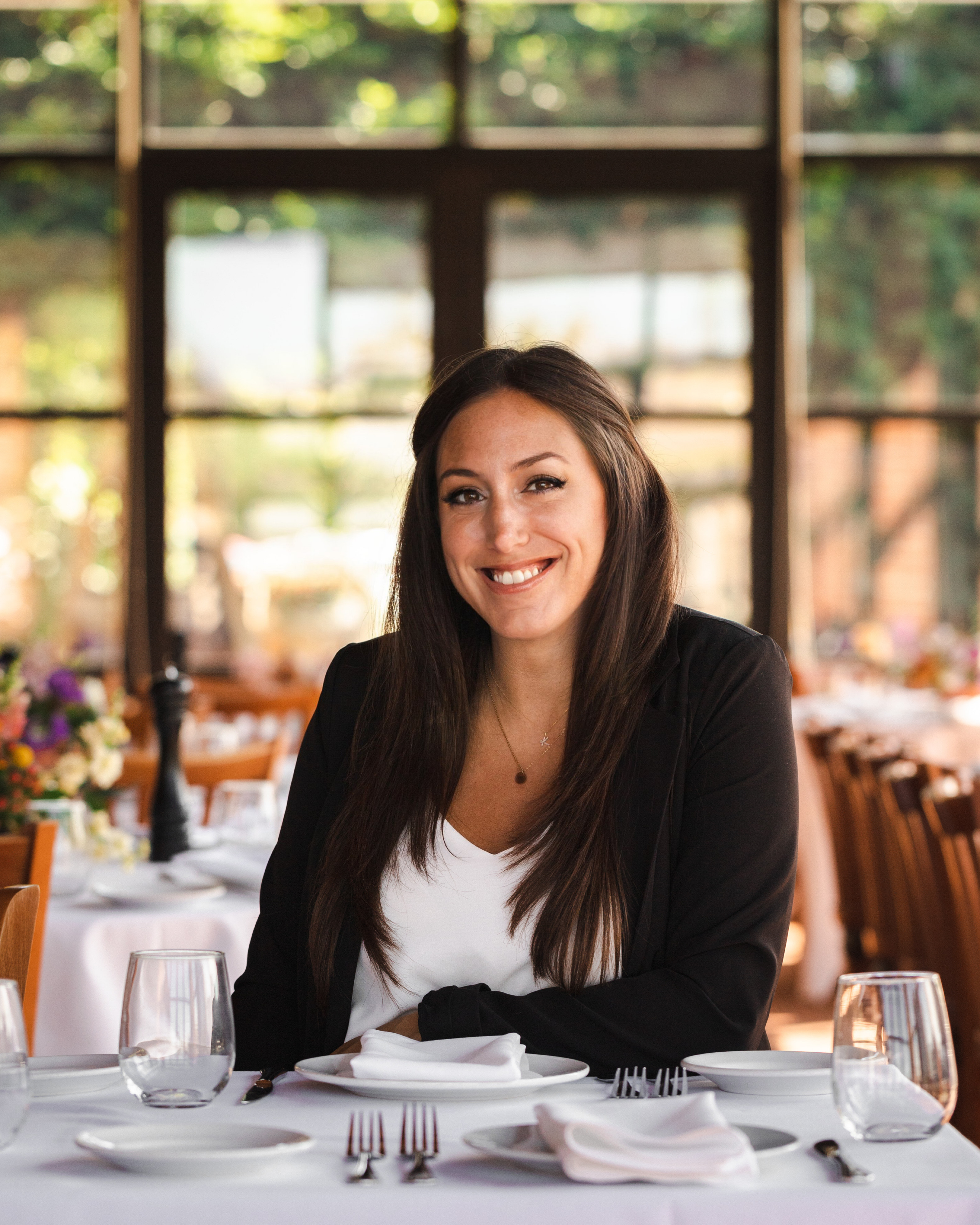 a woman sitting at a table with wine glasses