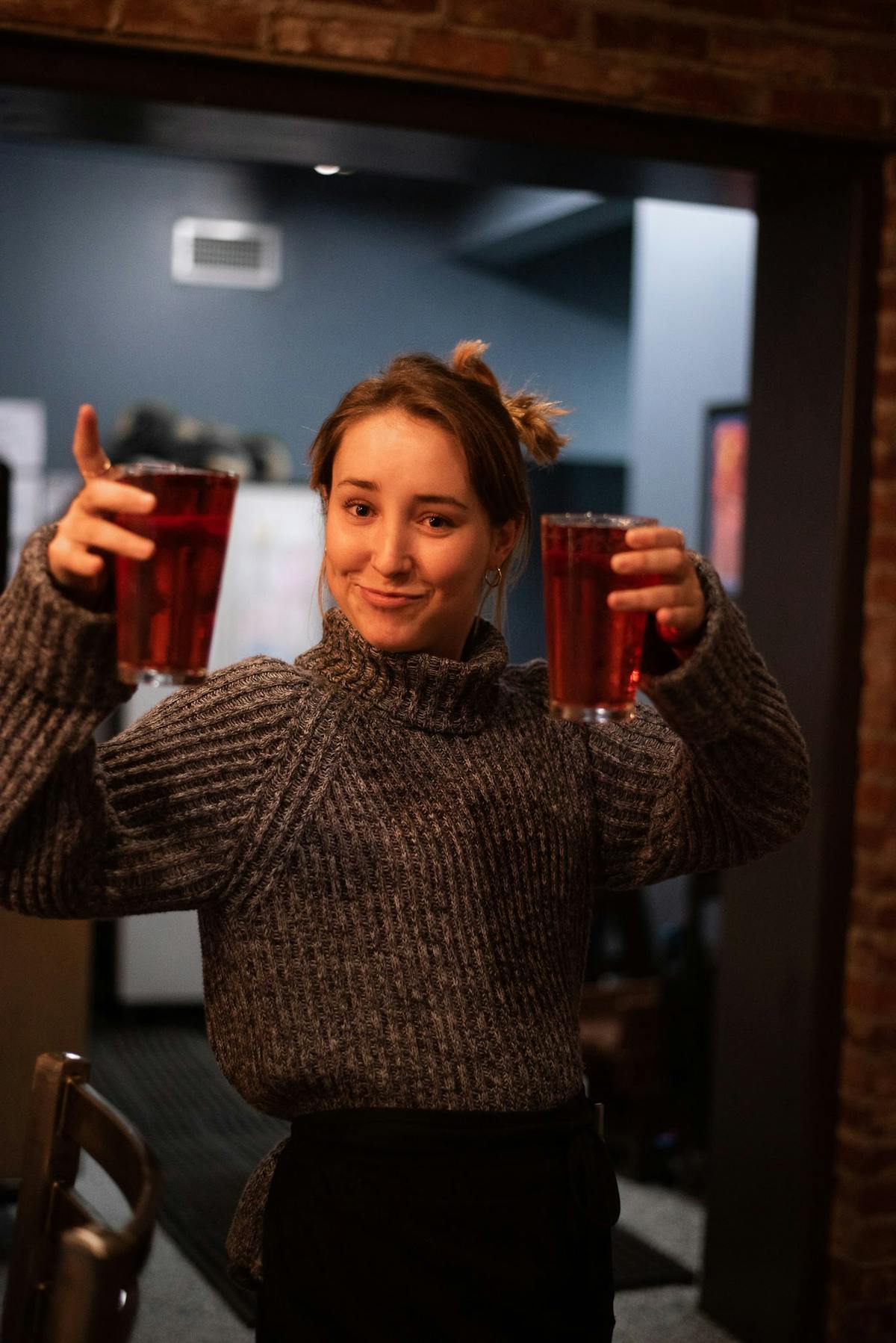 a woman standing in front of a mirror posing for the camera holding two beers