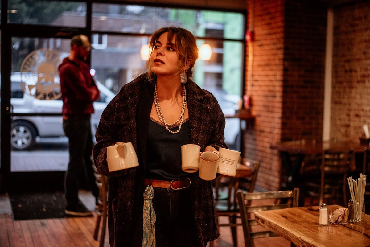 a person standing holding coffee mugs