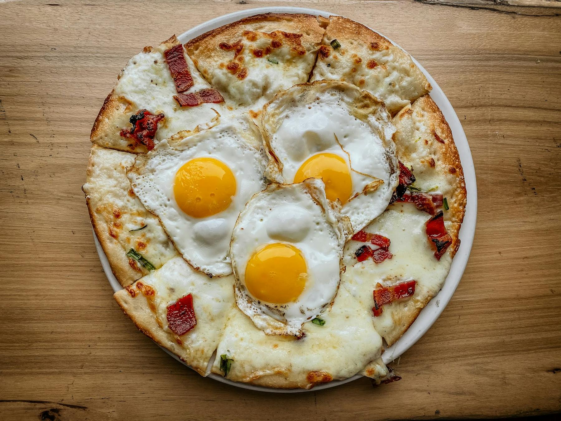 a pizza with three fried eggs on top