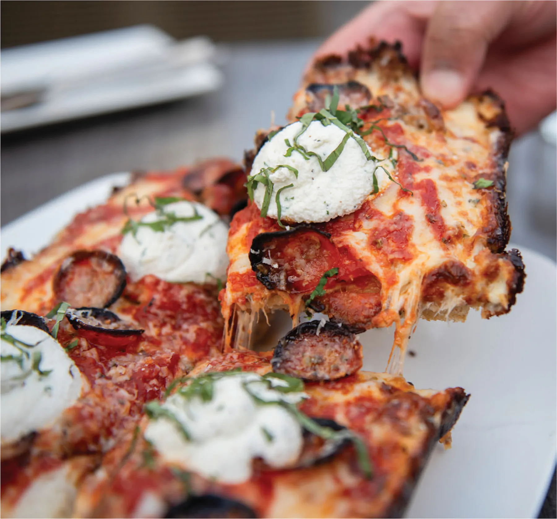 a hand holding a slice of pizza