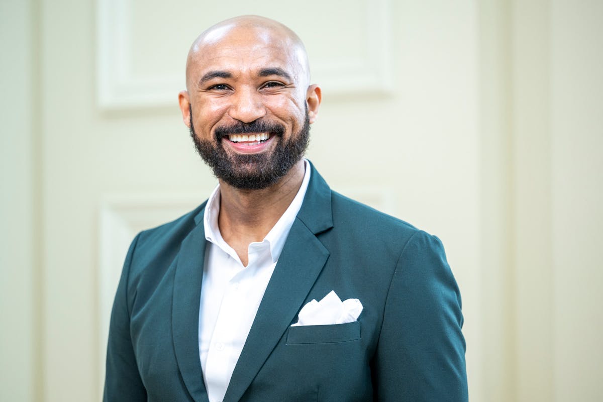 a man wearing a suit and tie smiling at the camera