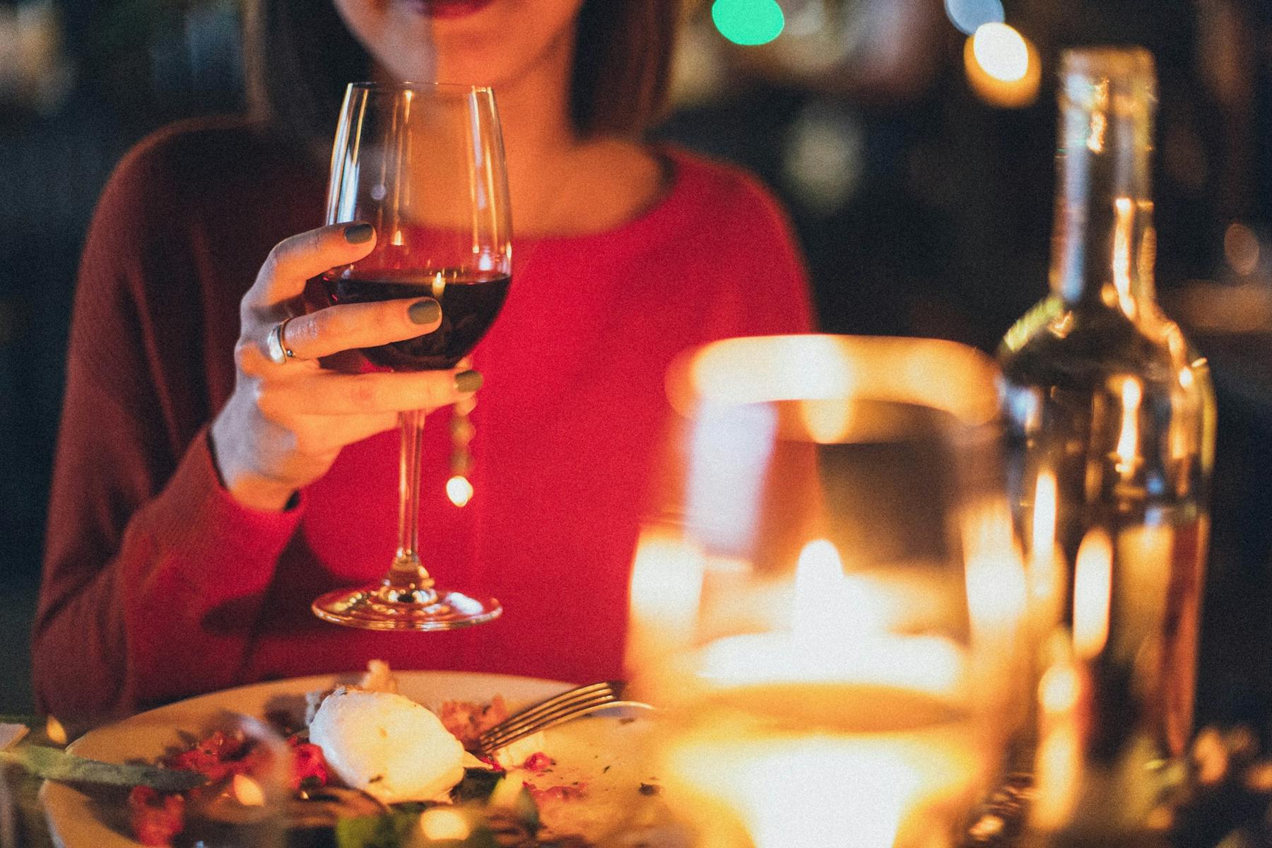a person sitting at a table holding a glass of wine