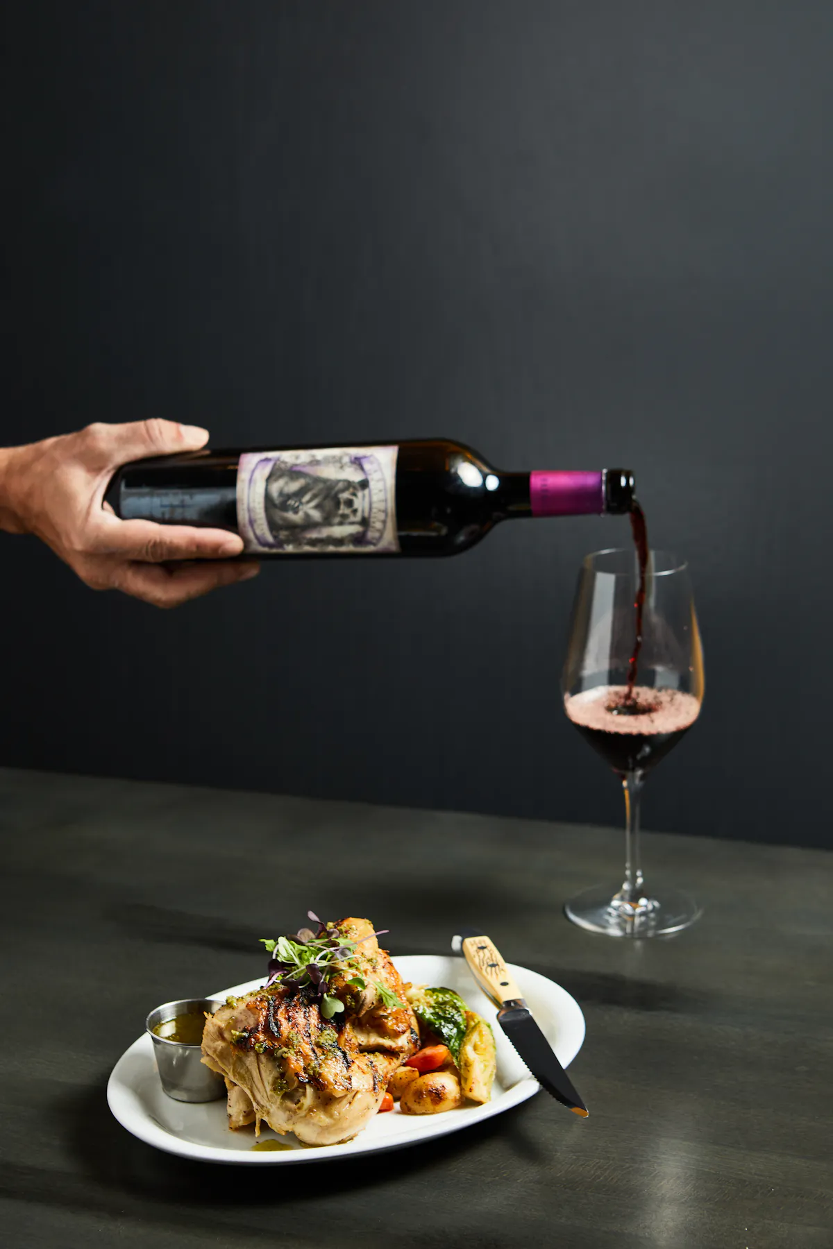 a woman sitting at a table holding a glass of wine
