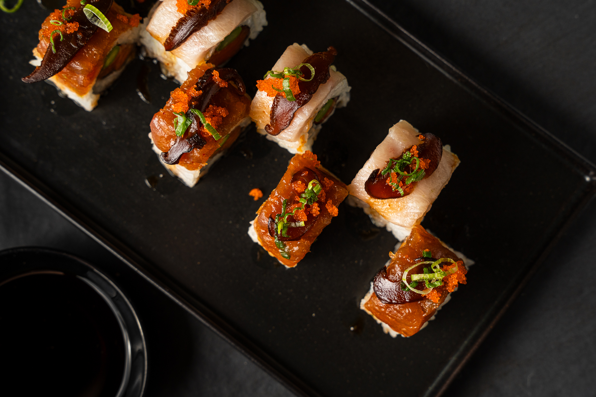 a plate of sushi on a black surface