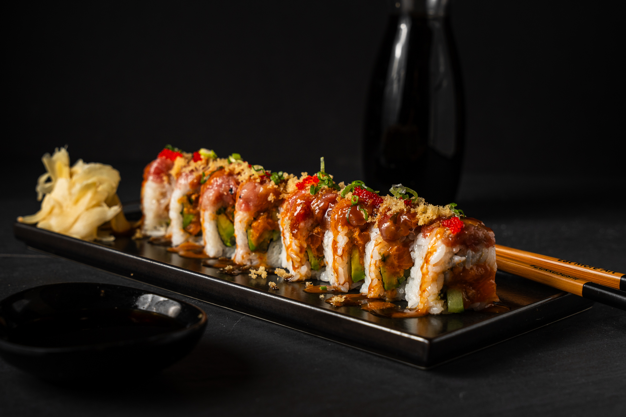 a plate of sushi with chopsticks and sauce