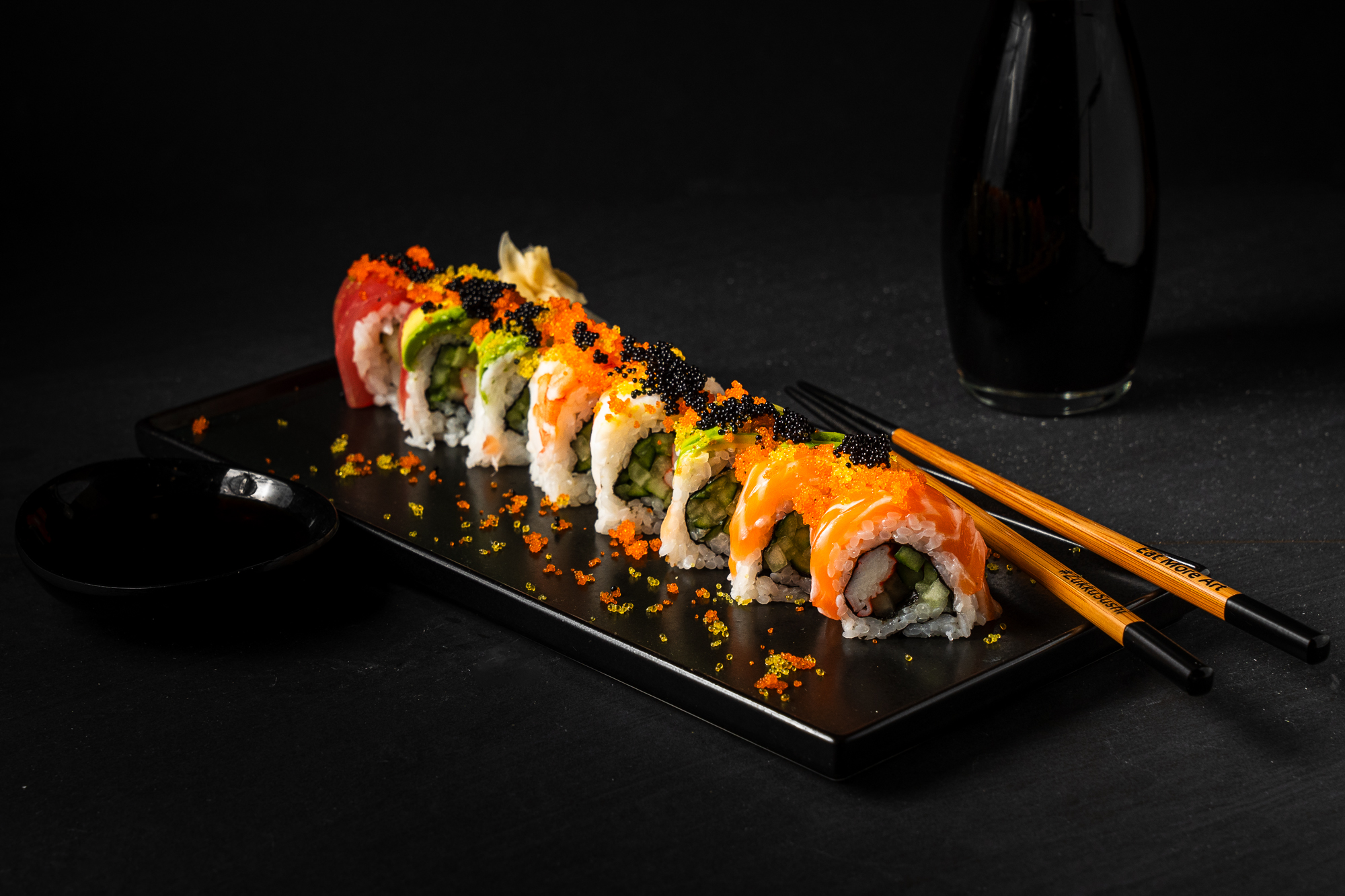 a plate of sushi with chopsticks and soy sauce