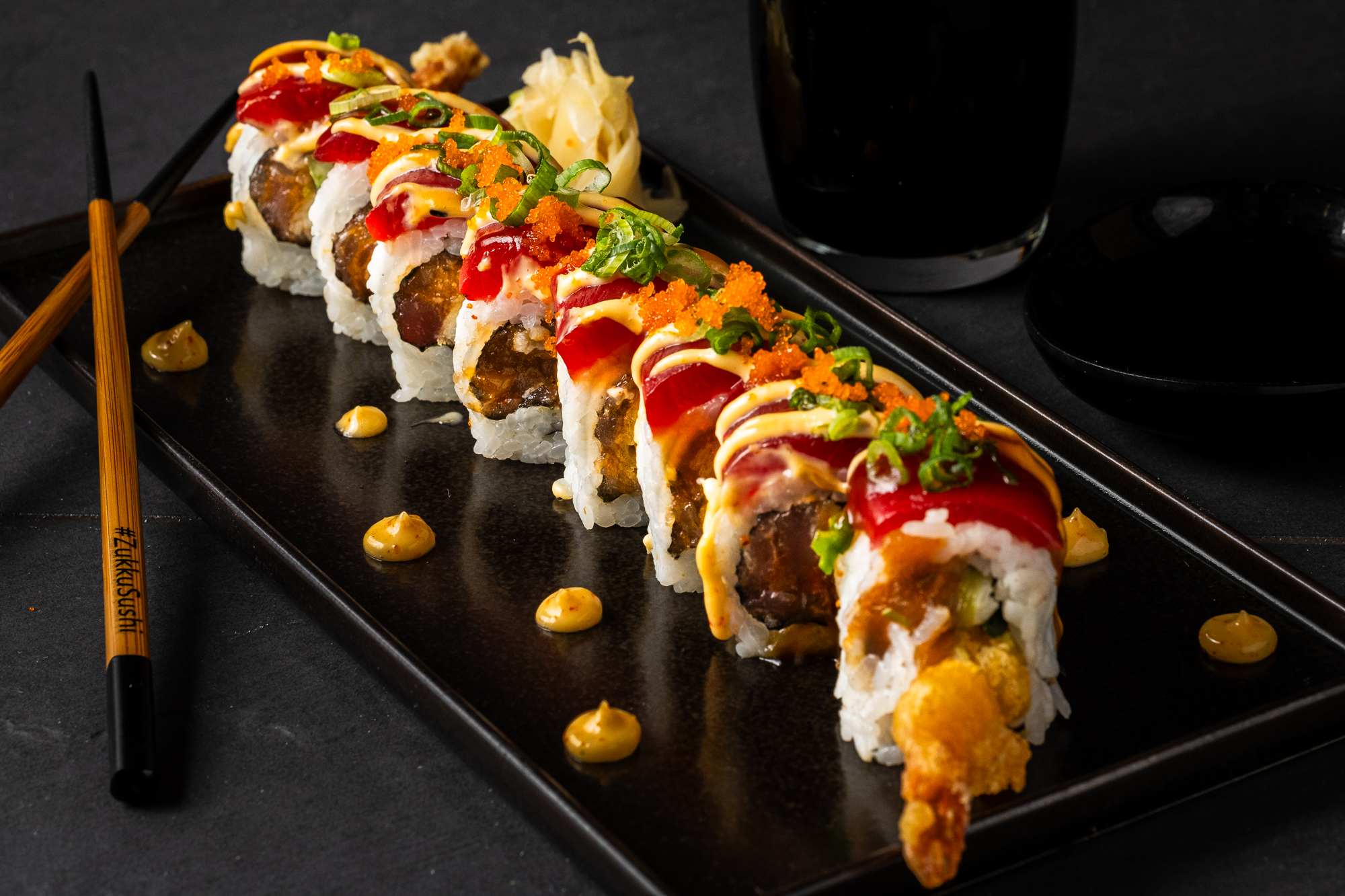 a plate of sushi with sauce and chopsticks