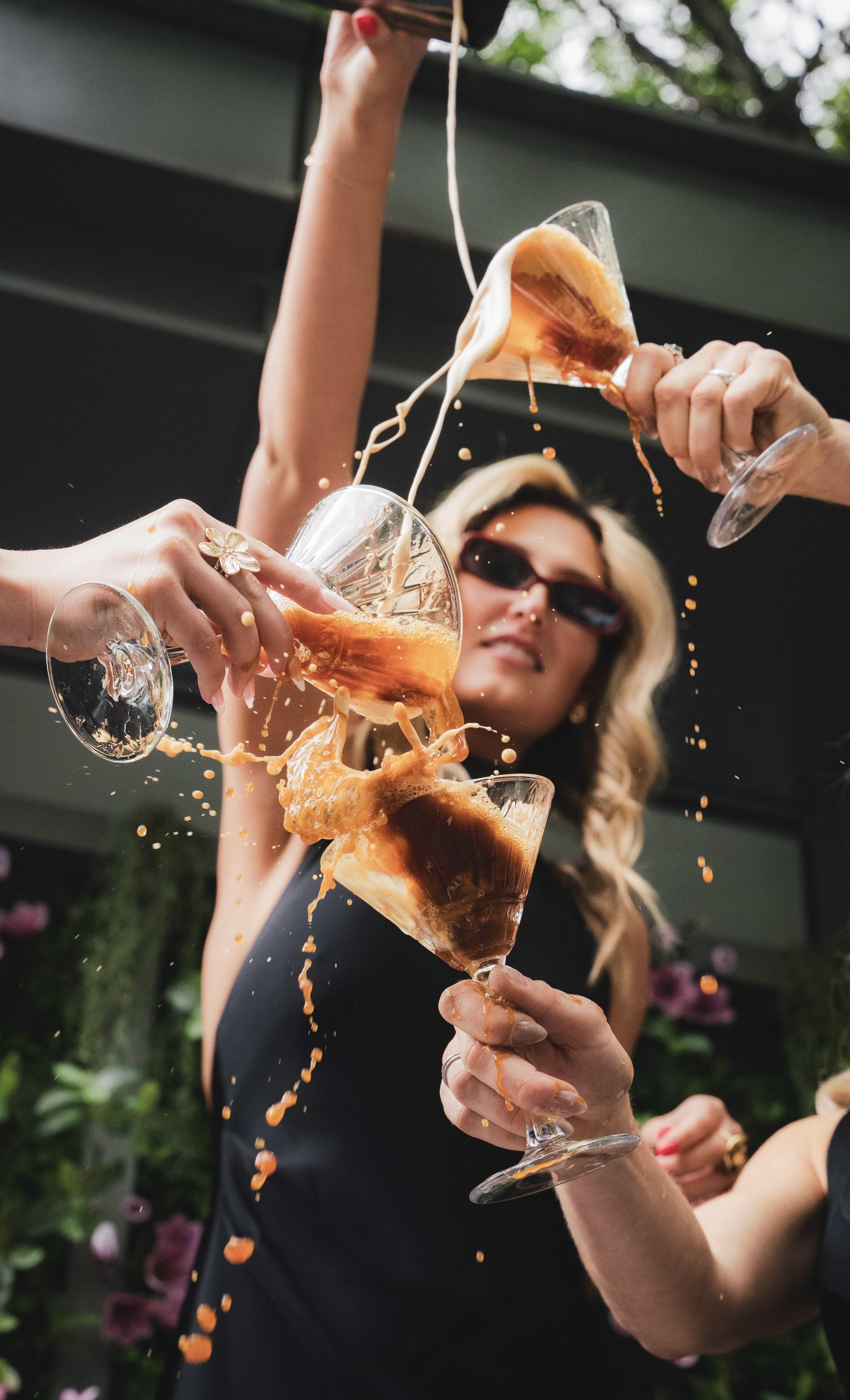 a group of people holding glasses with liquid pouring out of them