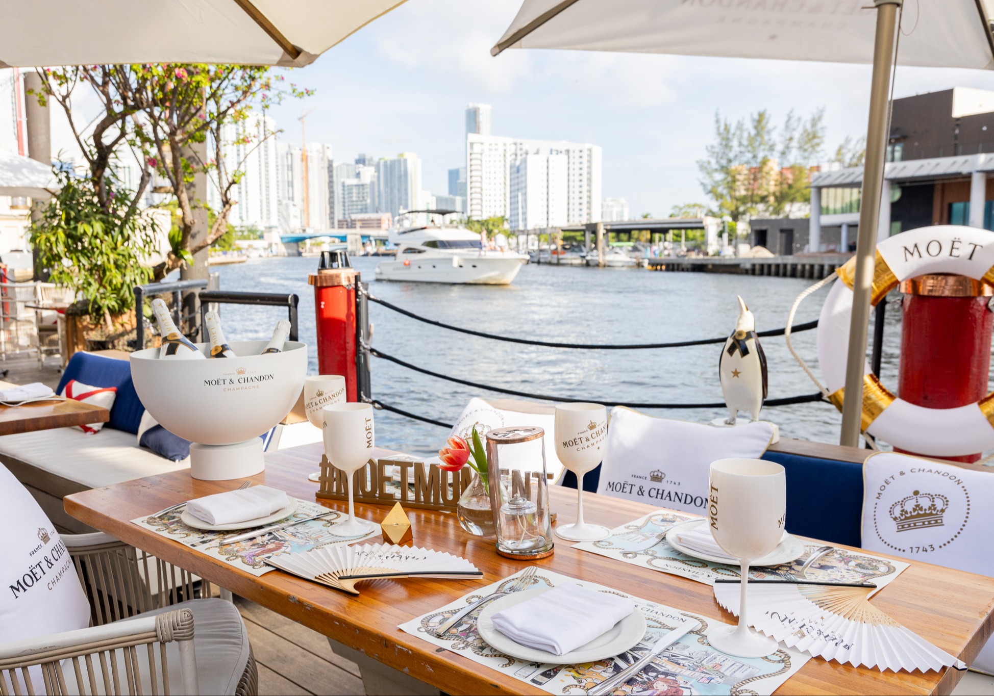 a table with white plates and glasses on it with a body of water in the background