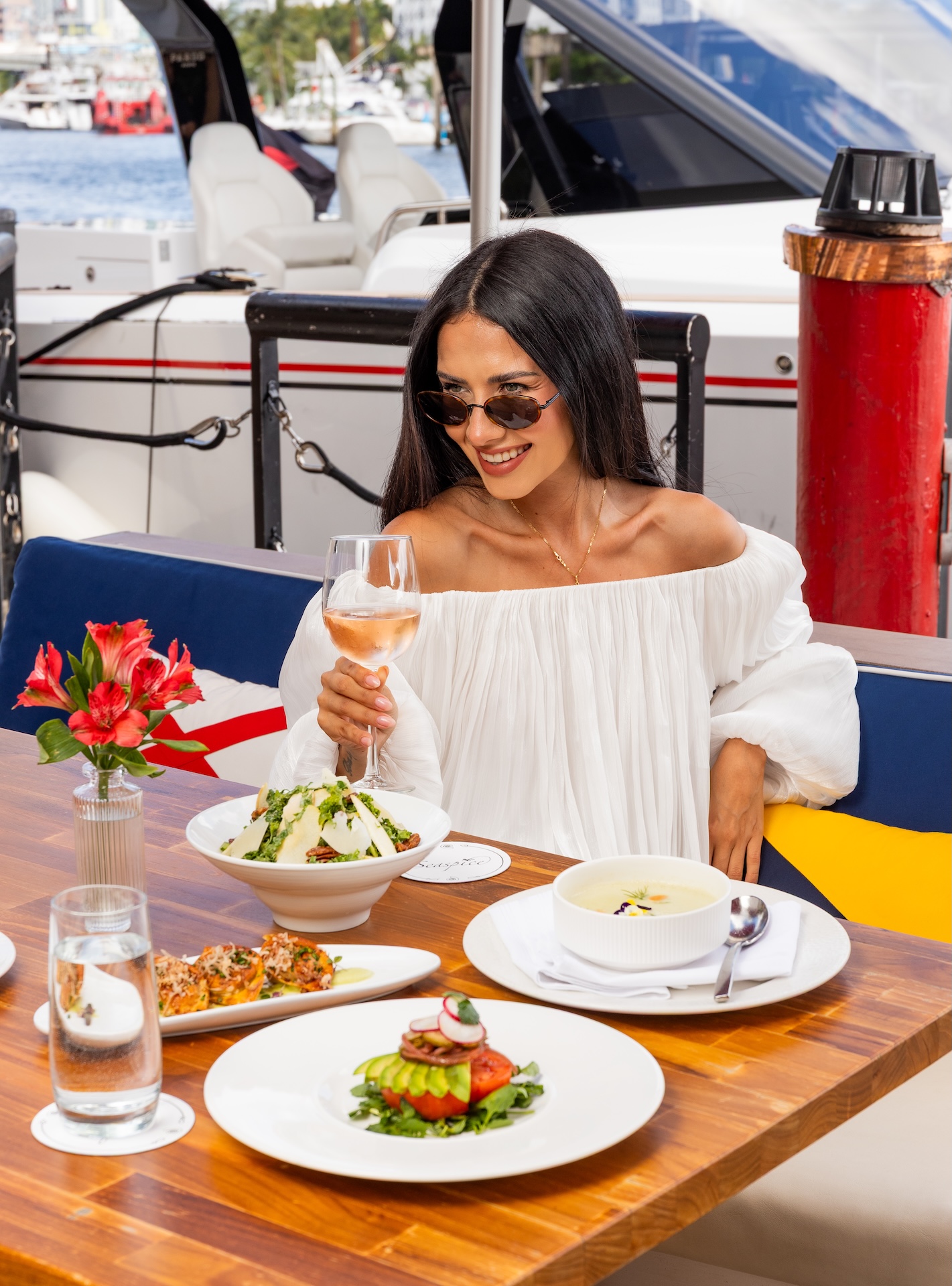 a woman sitting at a table with food and drinks