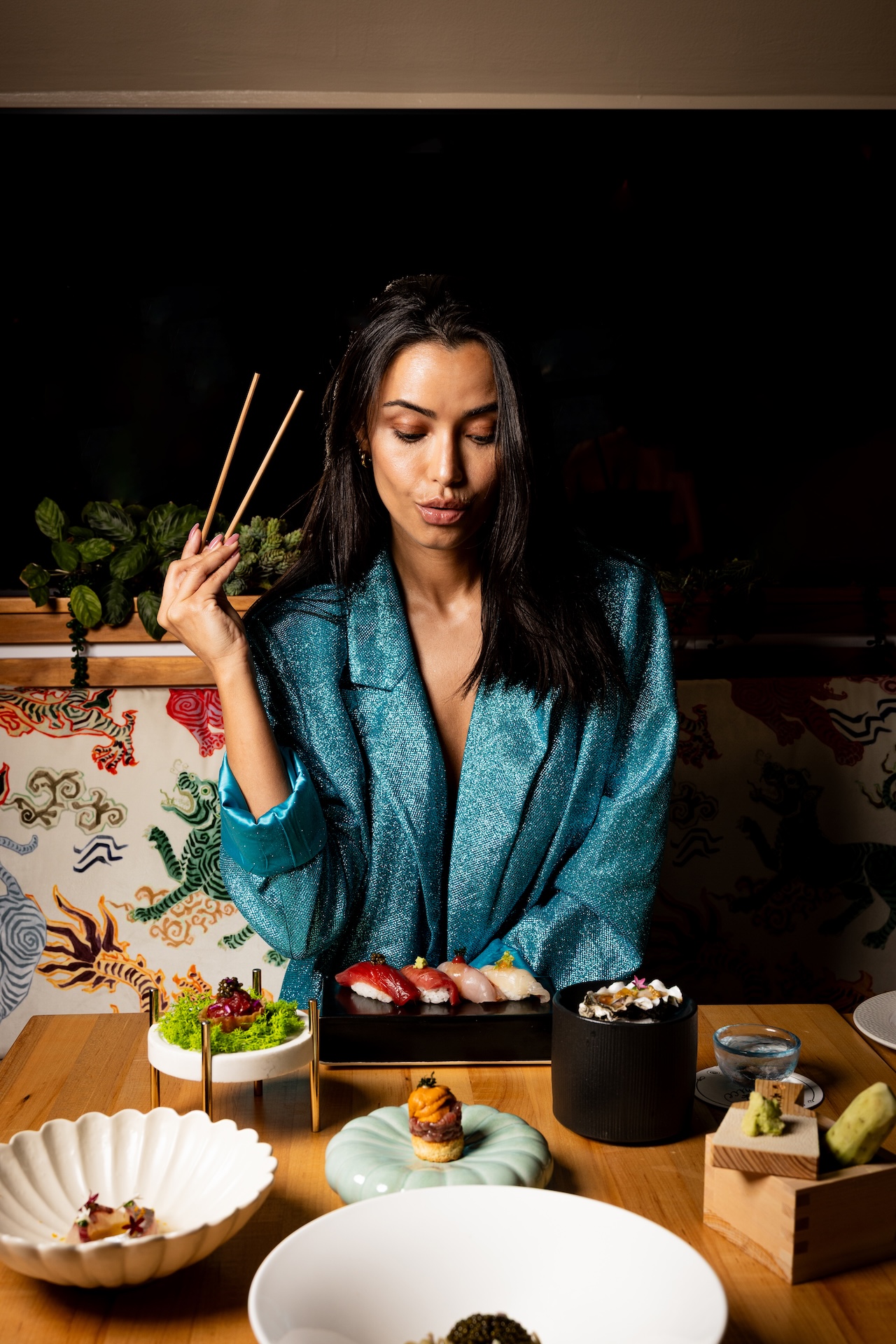 a woman holding chopsticks while sitting at a table with food