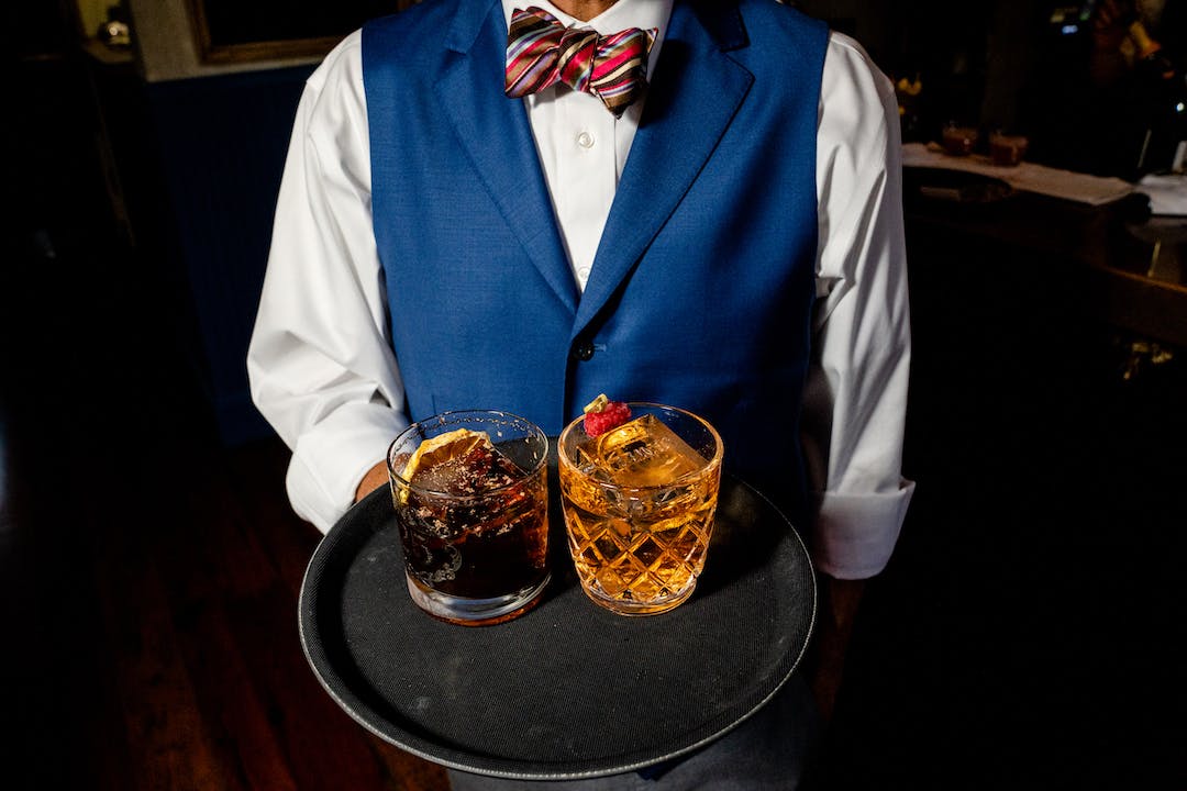 a person holding a tray with cocktails