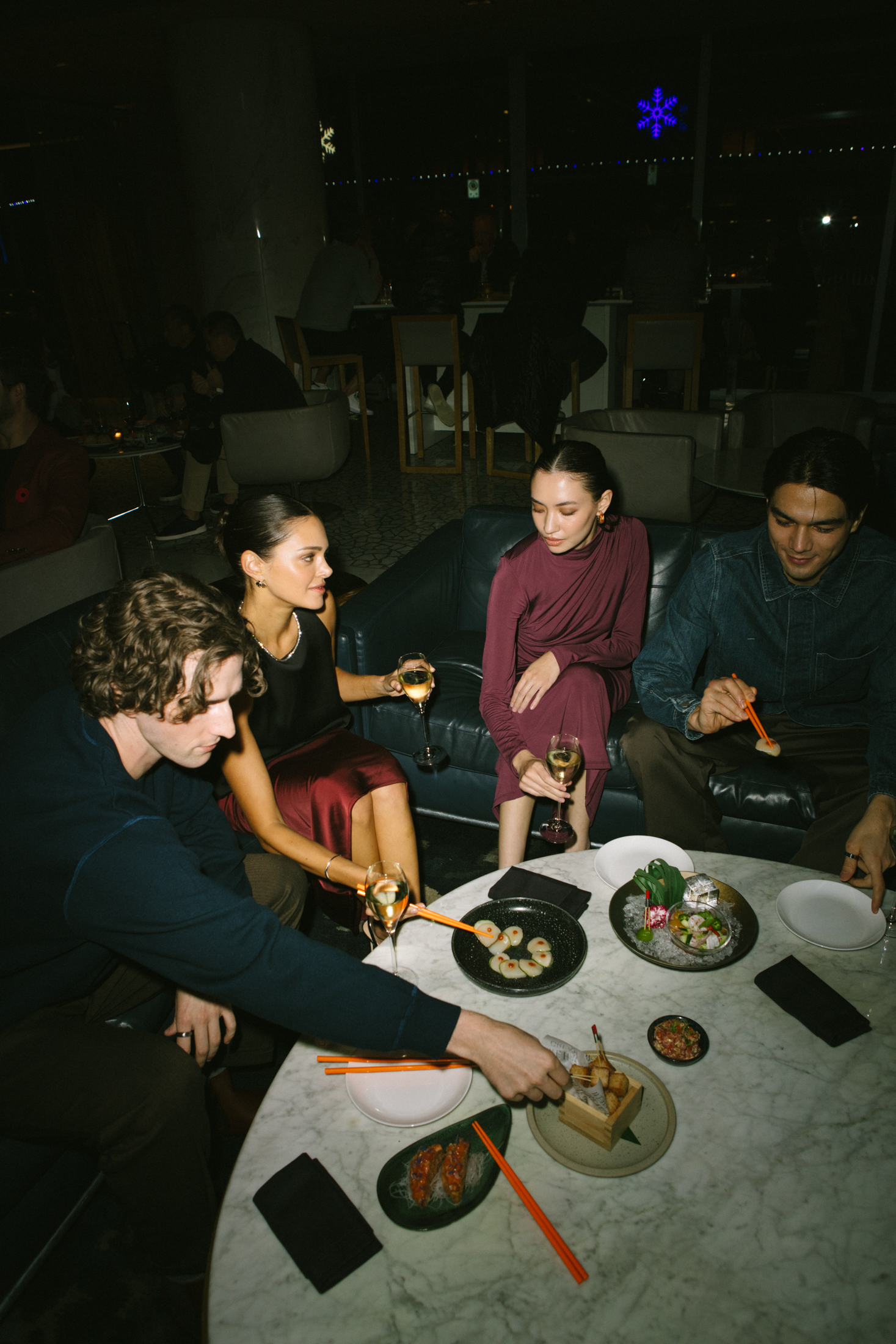 Four friends drinking champagne and eating sushi in the lounge