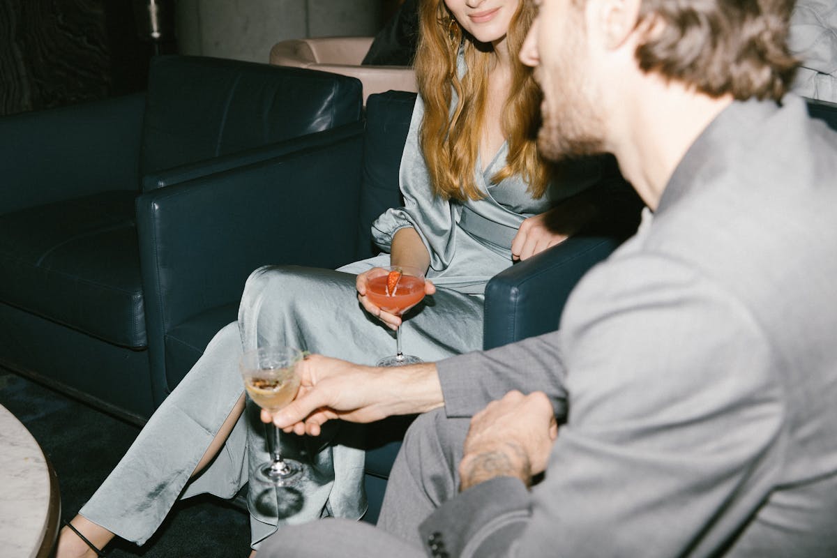 Man and woman sitting on blue lounge seats holding cocktails