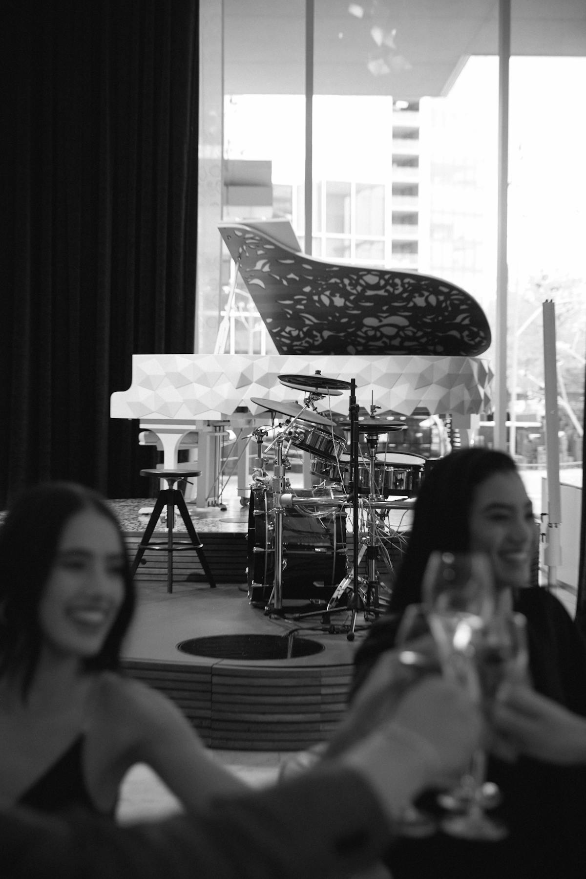 Friends cheersing champagne in front of a piano and drums set on a stage