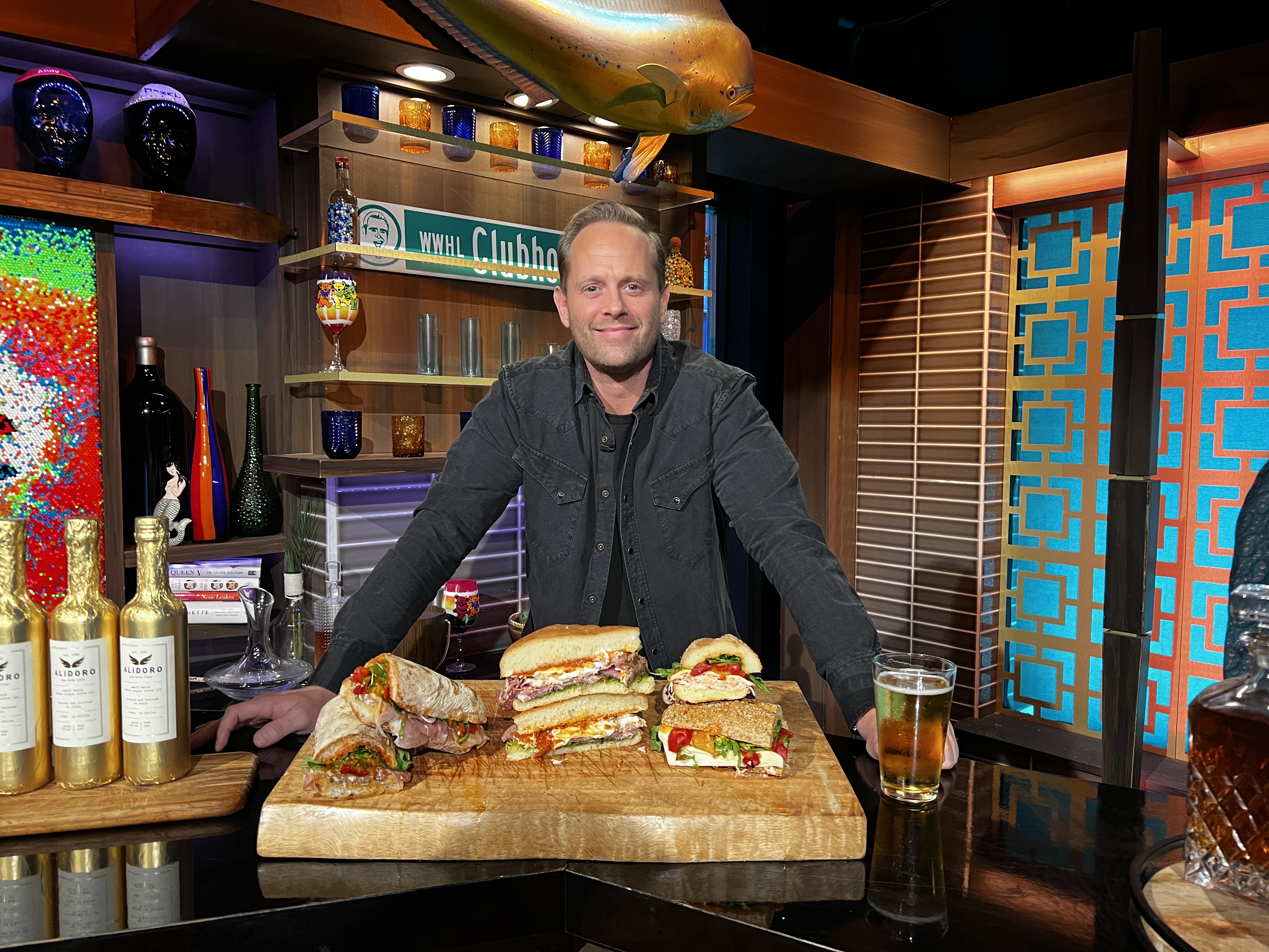 a man sitting at a table with sandwiches and a glass of beer