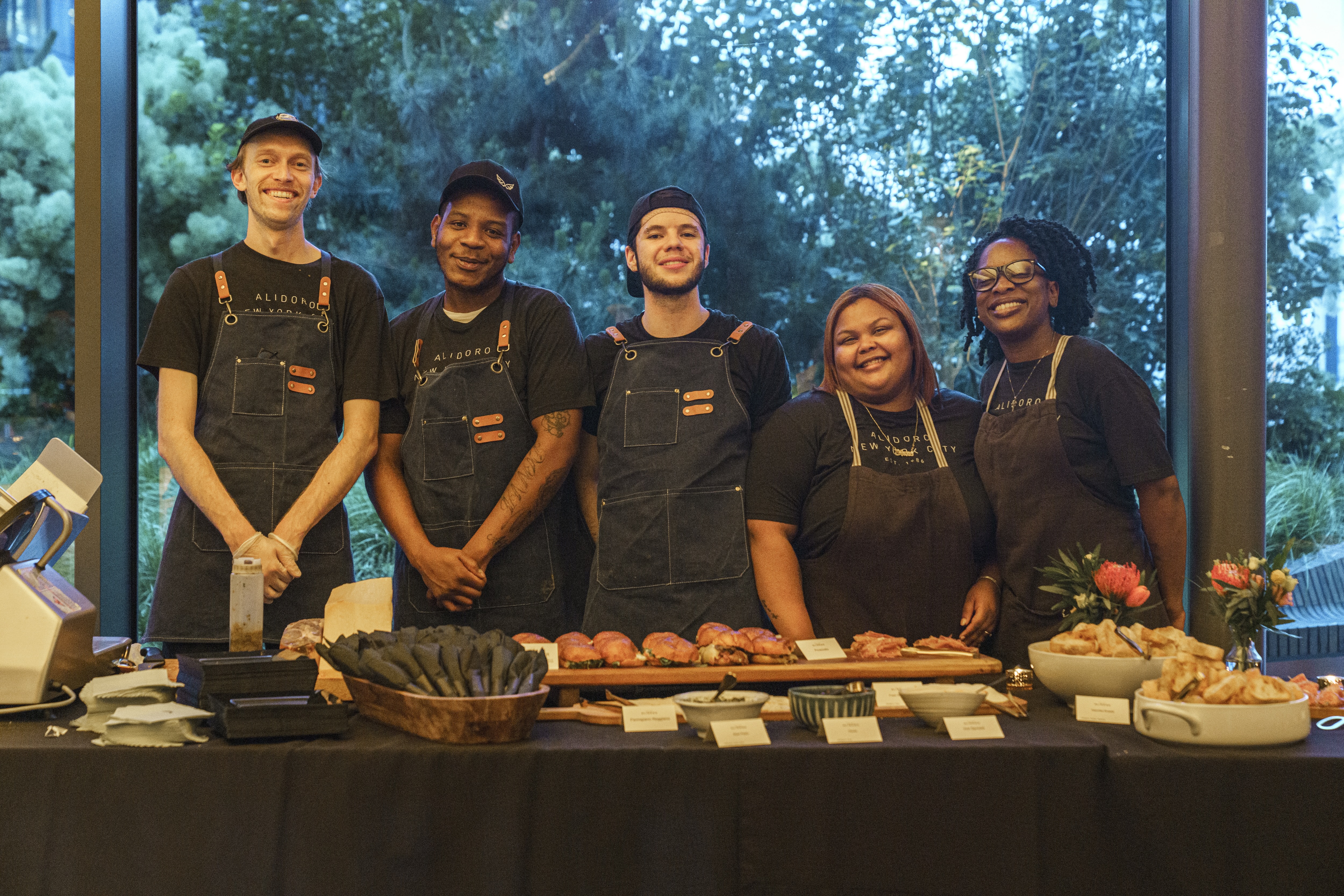 a group of people standing in front of a table with food