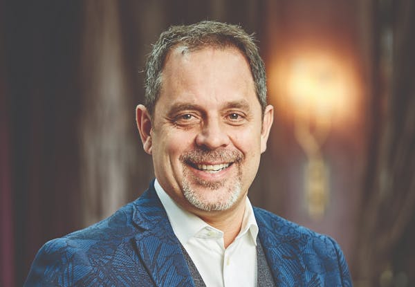 a man wearing a suit and tie smiling and looking at the camera