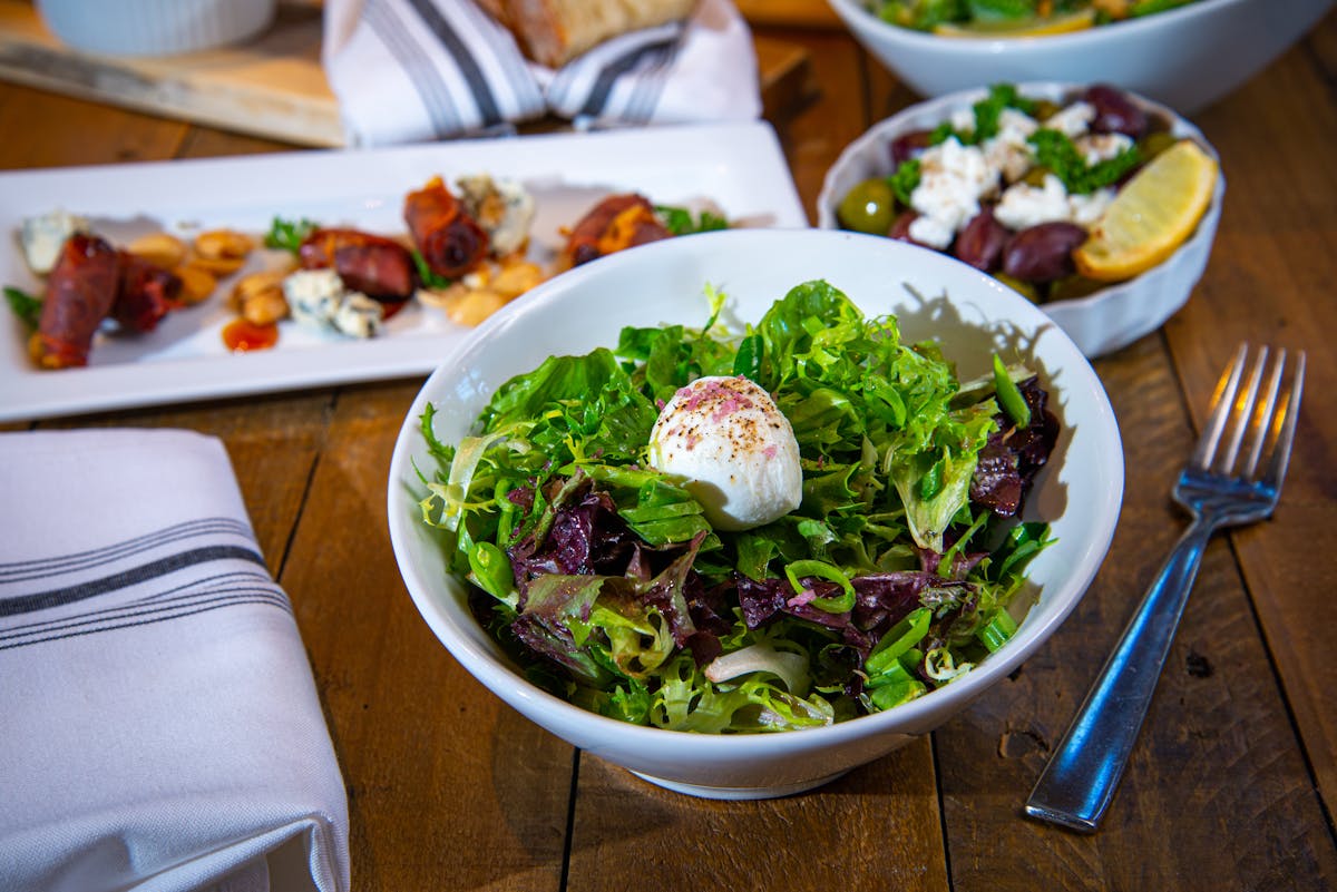 a bowl of salad on a plate on a table