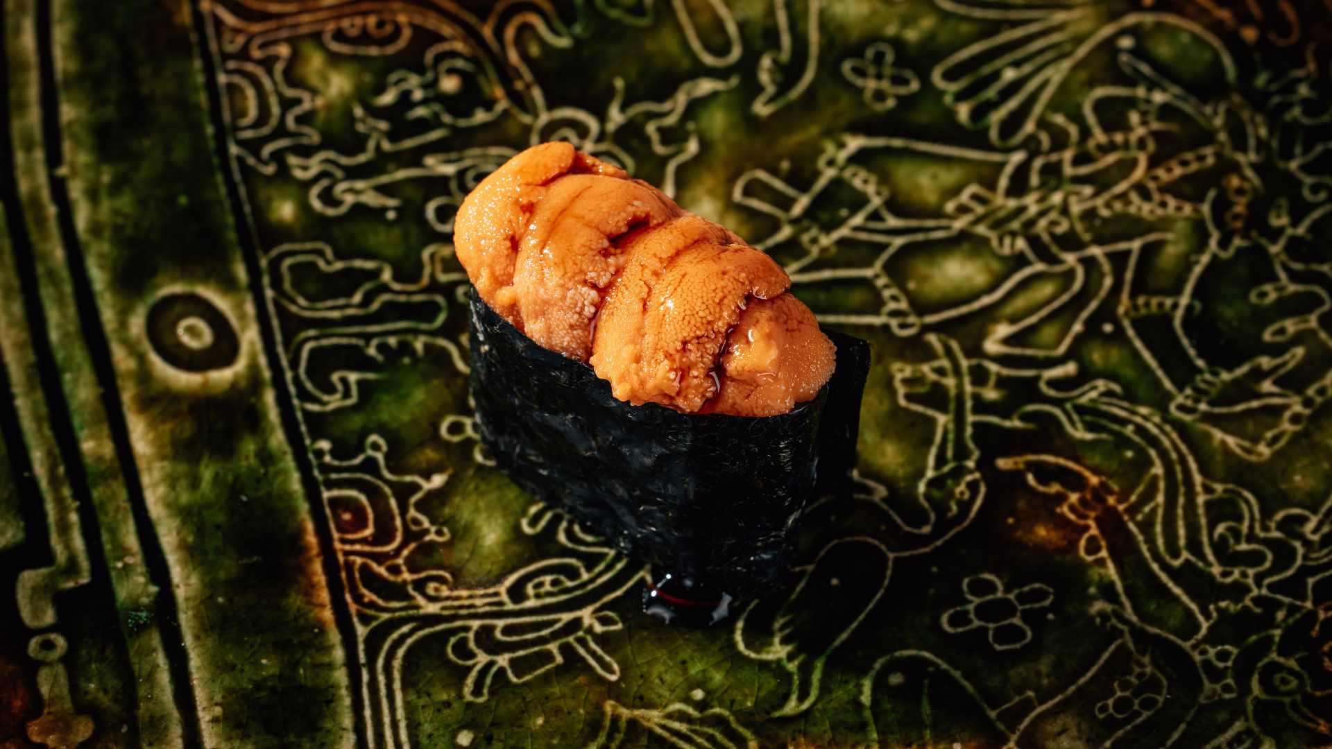 a sushi roll on a green and white patterned surface