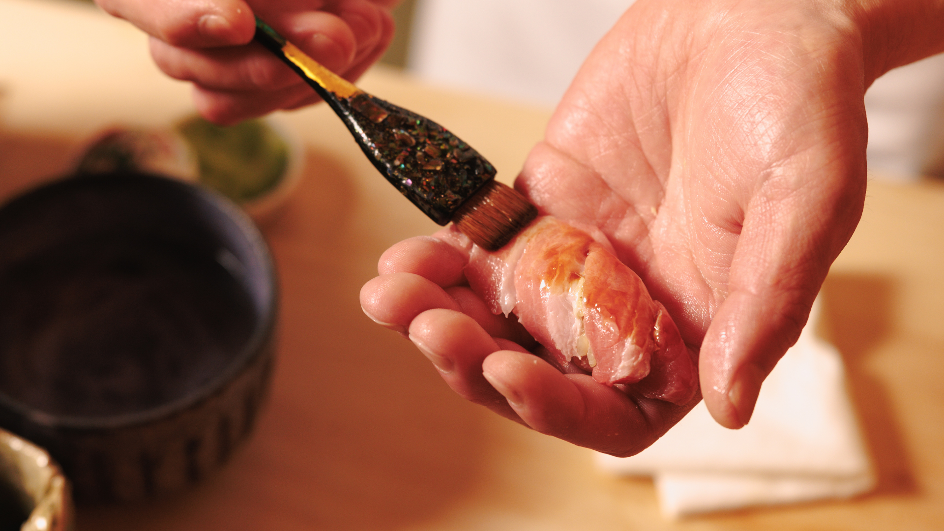 a person holding a piece of meat with a brush