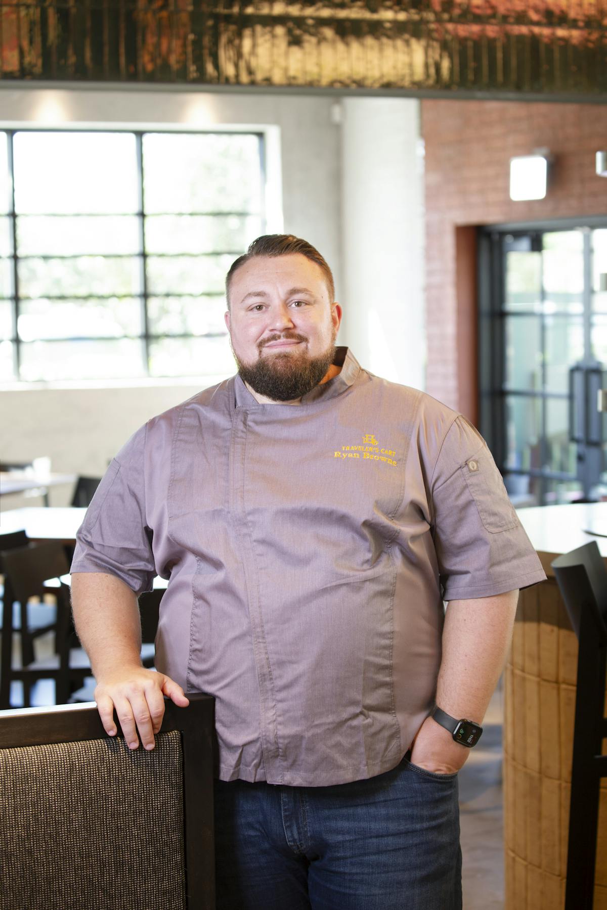 A man in a chef's uniform stands confidently in front of a table, ready to prepare a meal